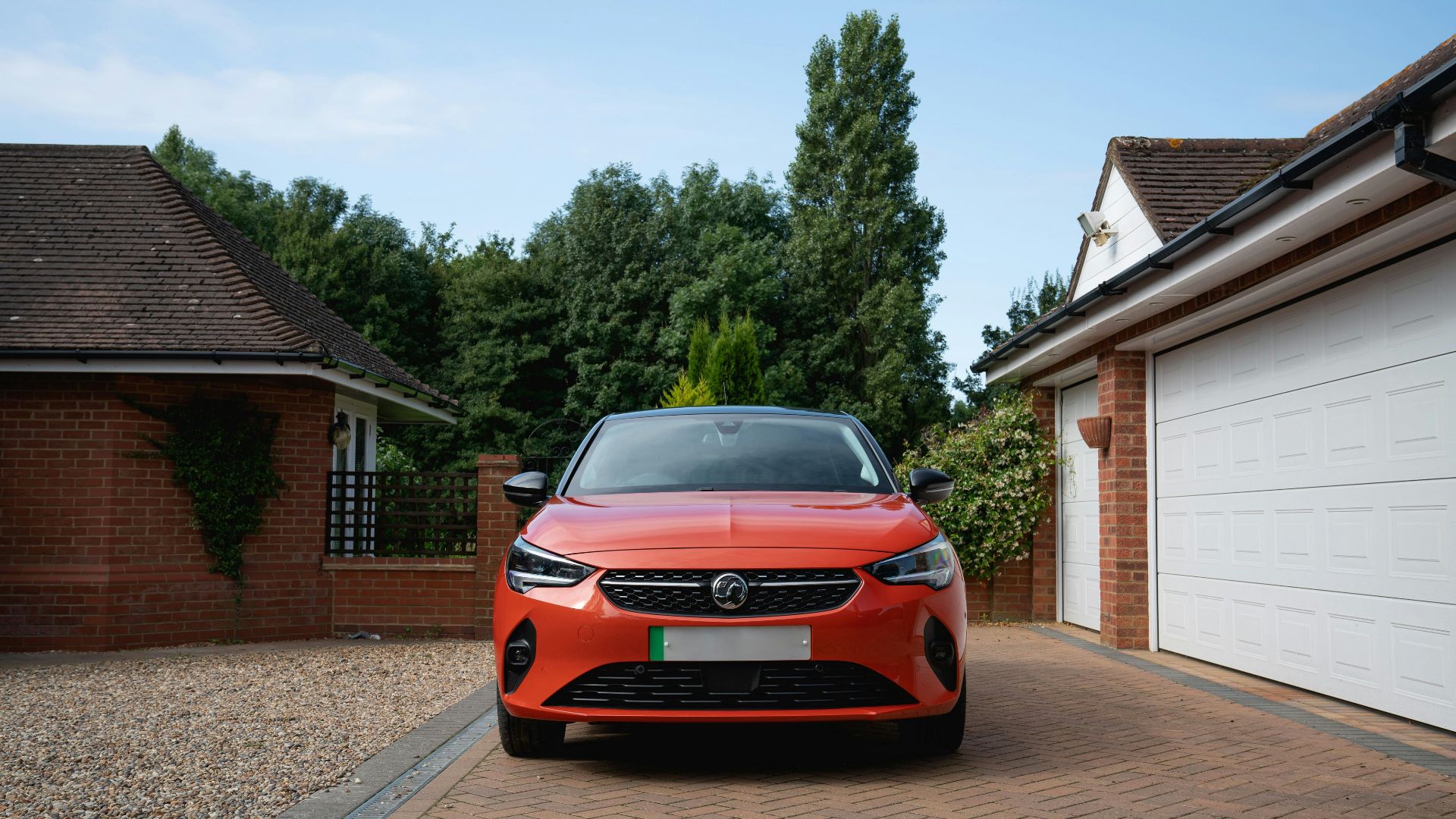 Orange car parked in driveway between garages.