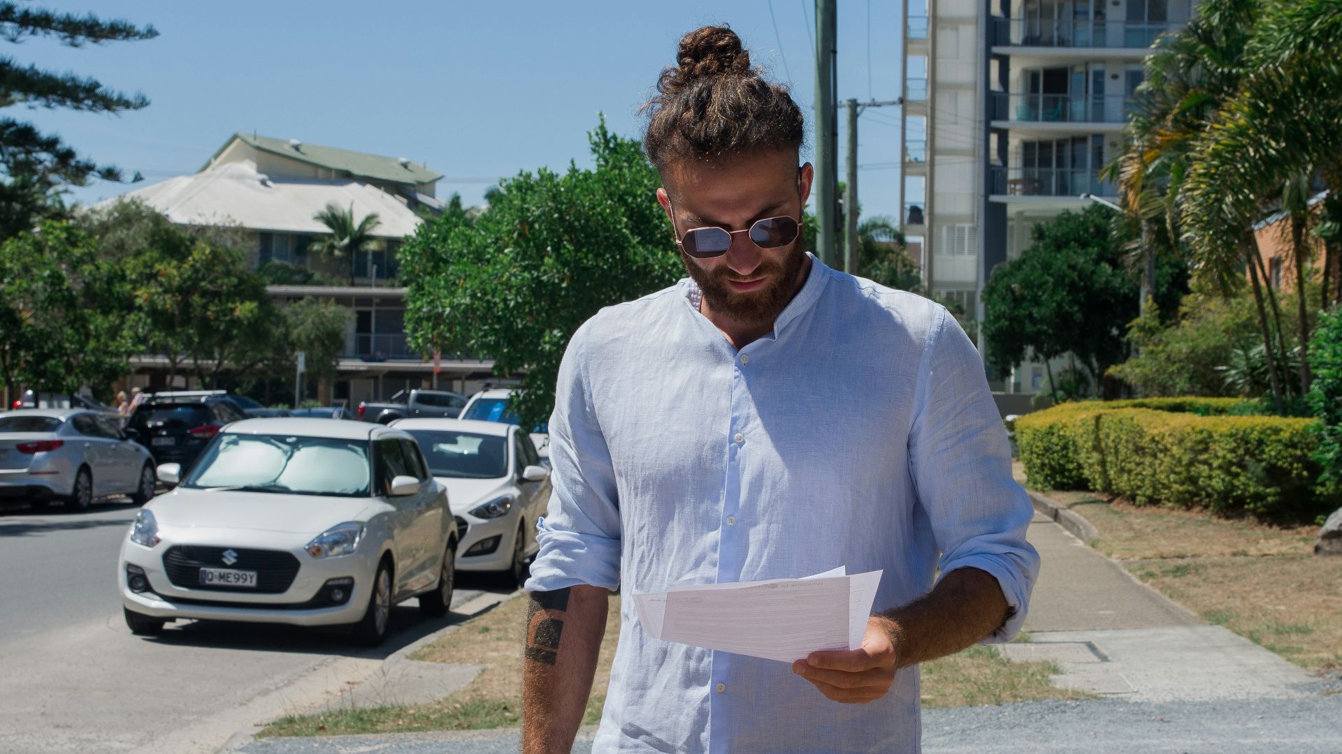 man in white button up t-shirt holding white printer paper