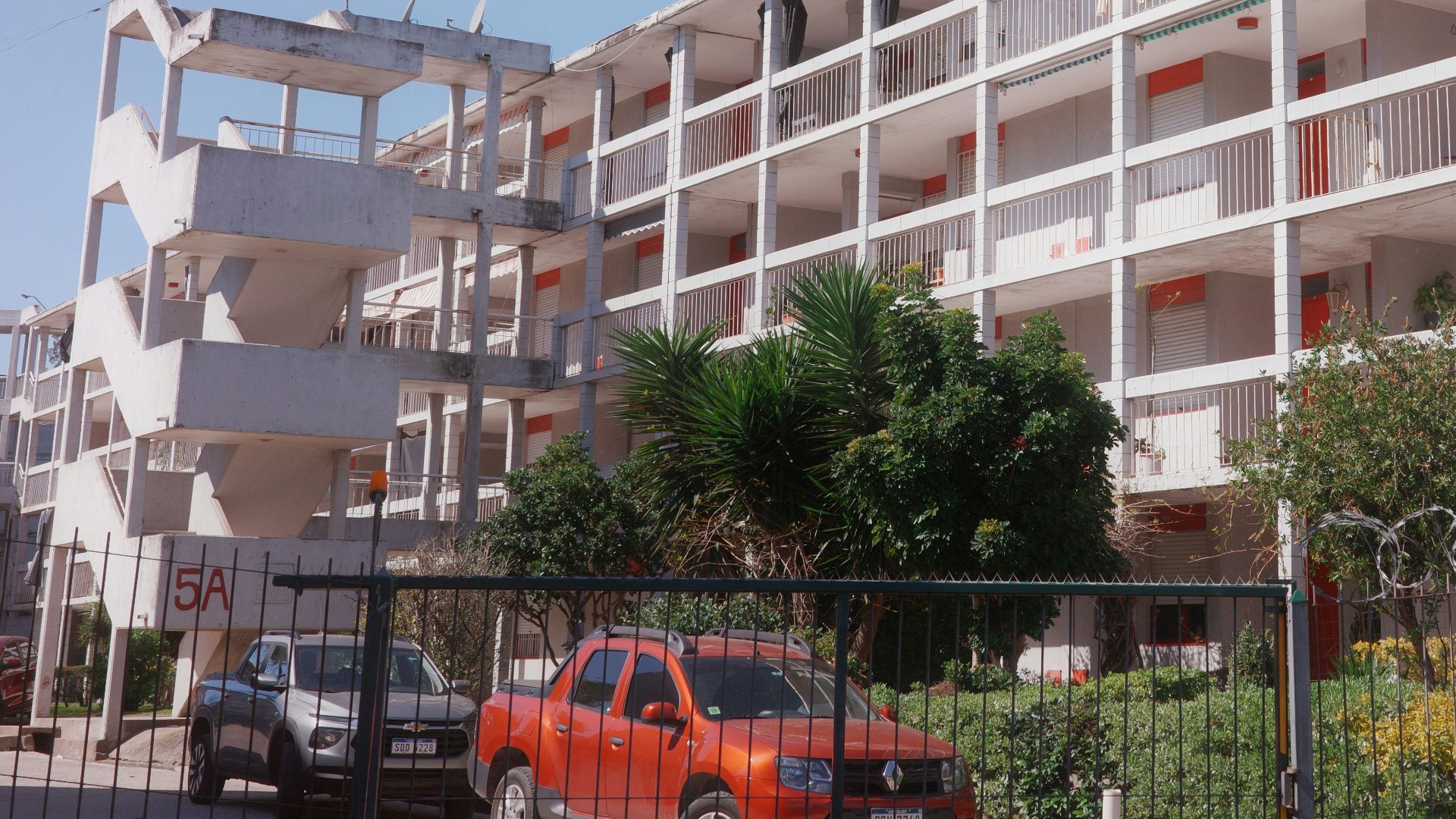 Modern apartment building with balconies and cars.