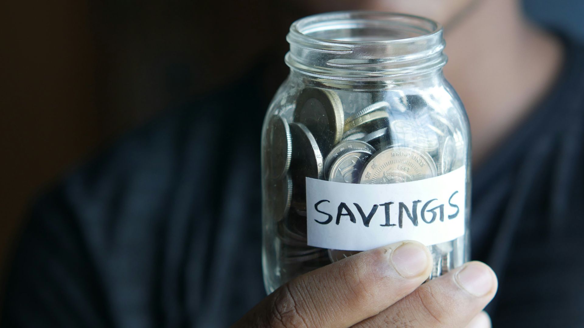 a man holding a jar with a savings label on it