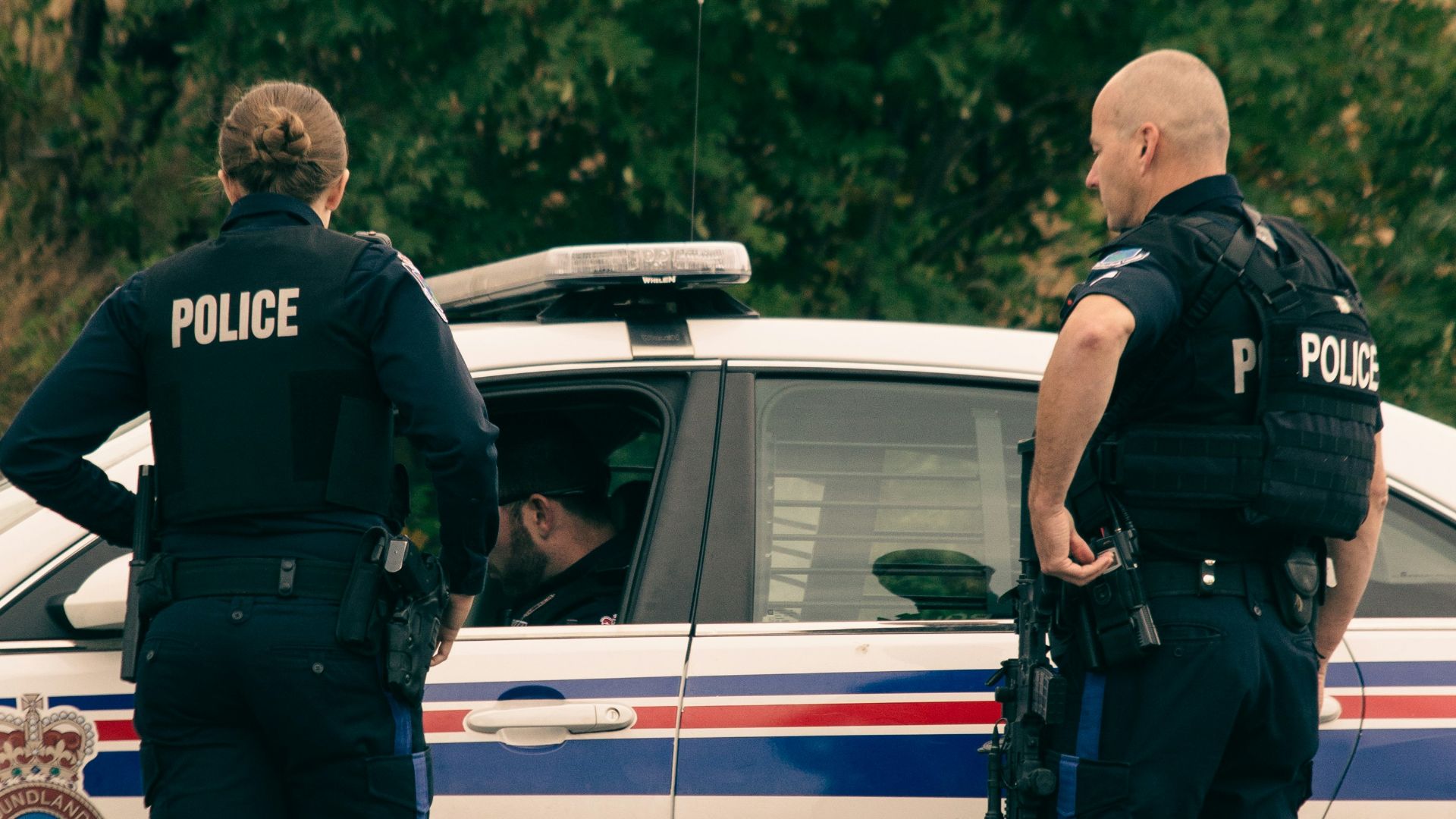 2 police men standing on white police car during daytime