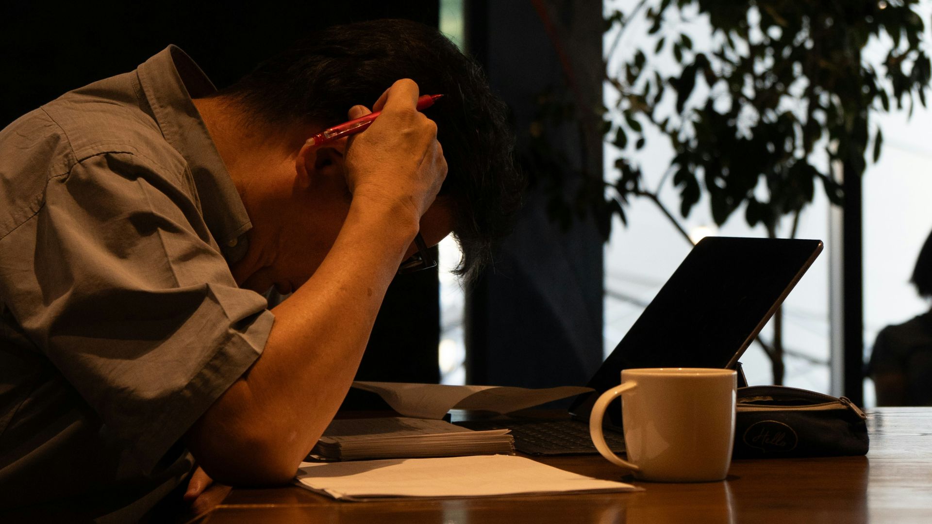 A man sitting at a table with his head in his hands