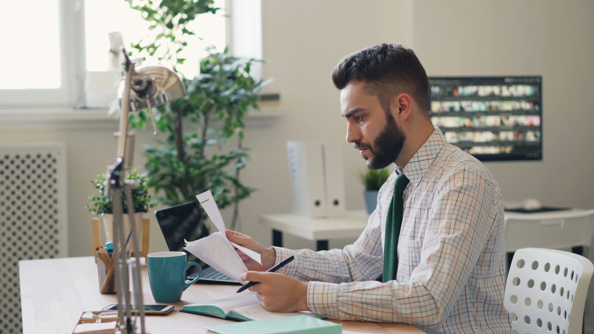 a man sitting at a desk with a laptop and papers