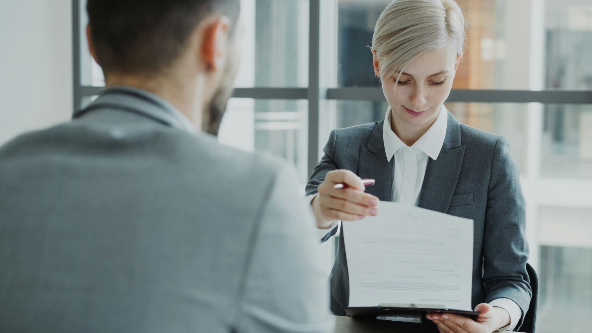 Woman in suit shows document to man