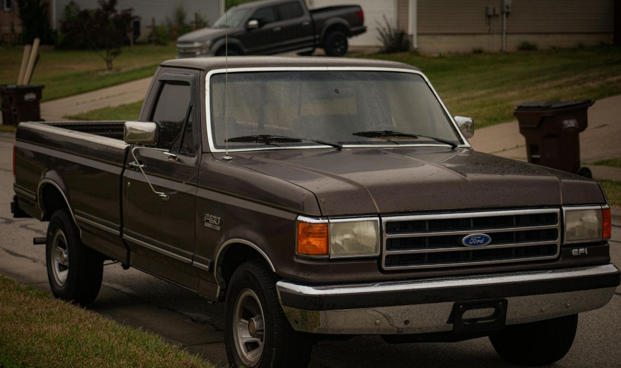 Classic brown pickup truck parked on a quiet suburban street, showcasing vintage automotive design