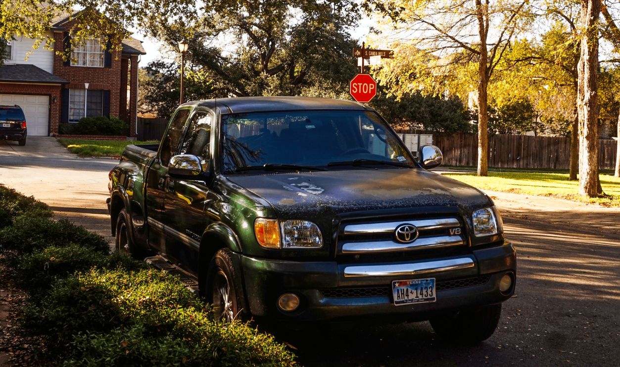 A black pickup truck parked on a quiet suburban street lined with trees and houses