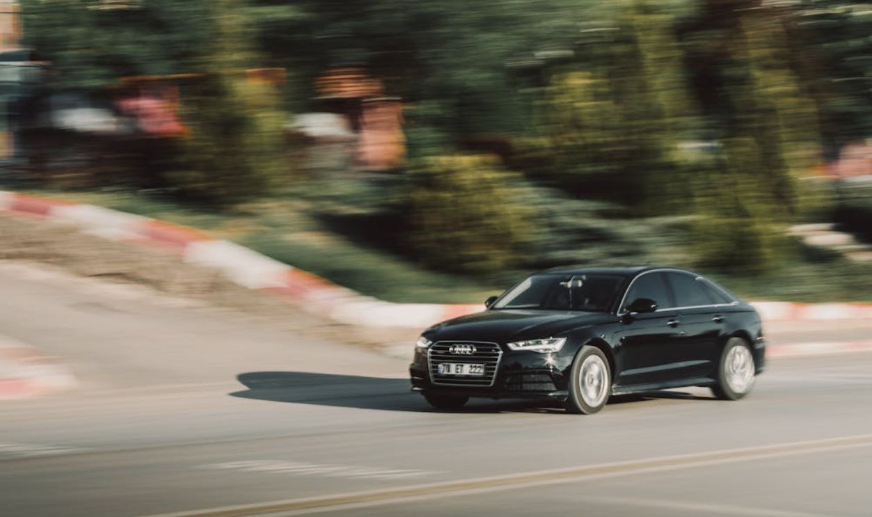 Dynamic shot of a black Audi car on a city road, emphasizing speed and motion.
