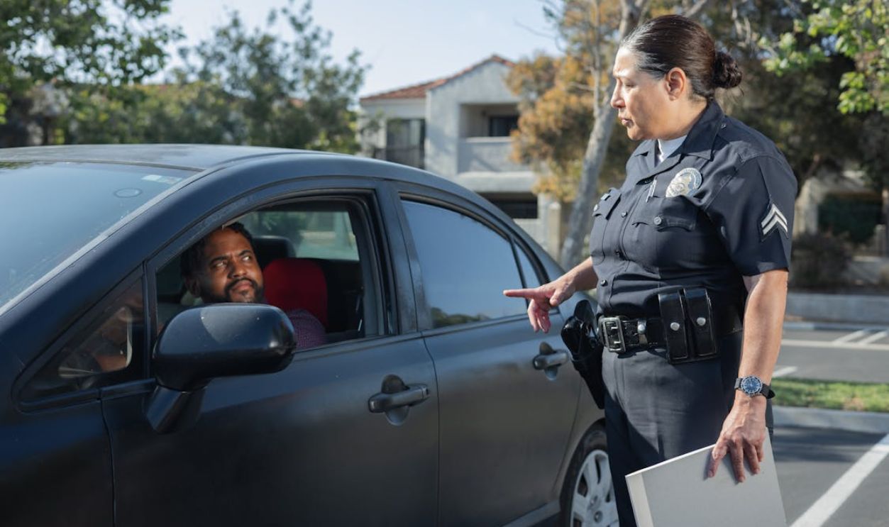 A police officer interacts with a driver during a daytime traffic stop on a residential street.