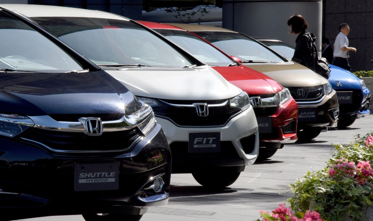 People walk amidst vehicles by Japan's Honda Motor displayed in front of the company's headquarters in Tokyo on May 13, 2016. Honda Motor said on May 13 its full-year net profit dropped by a third, pressured by the exploding airbag crisis at key supplier Takata. 