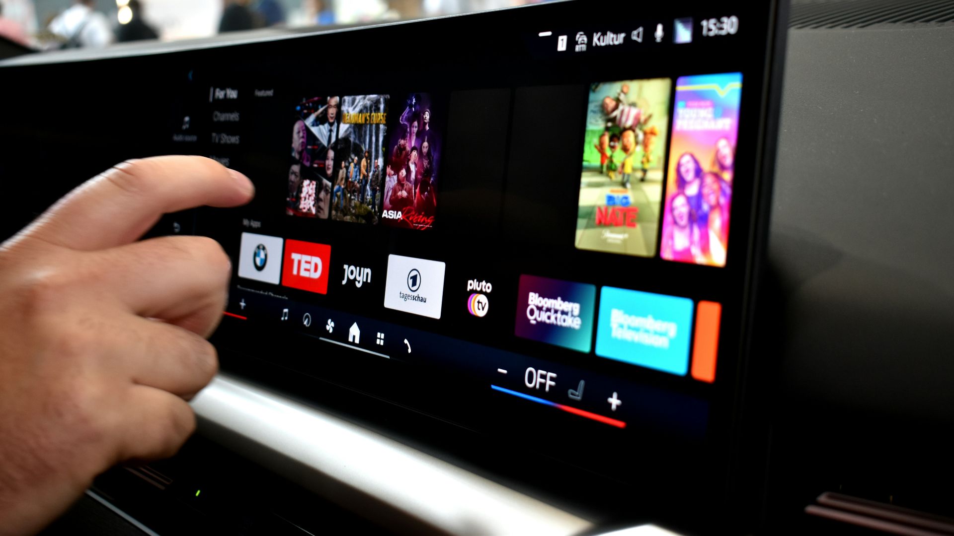 Person touching a car infotainment screen with media options.