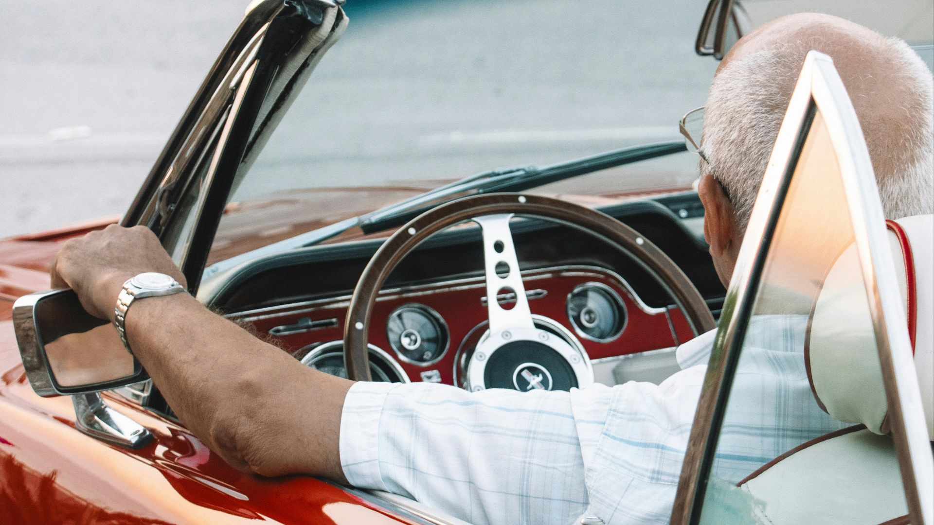 a man driving a red convertible car down a street