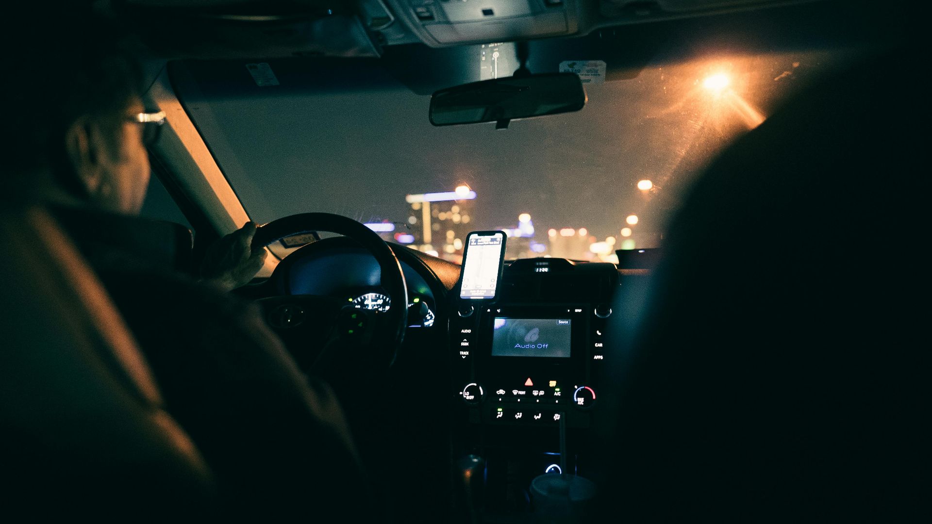 View from inside a car showing a driver navigating a city at night using GPS.