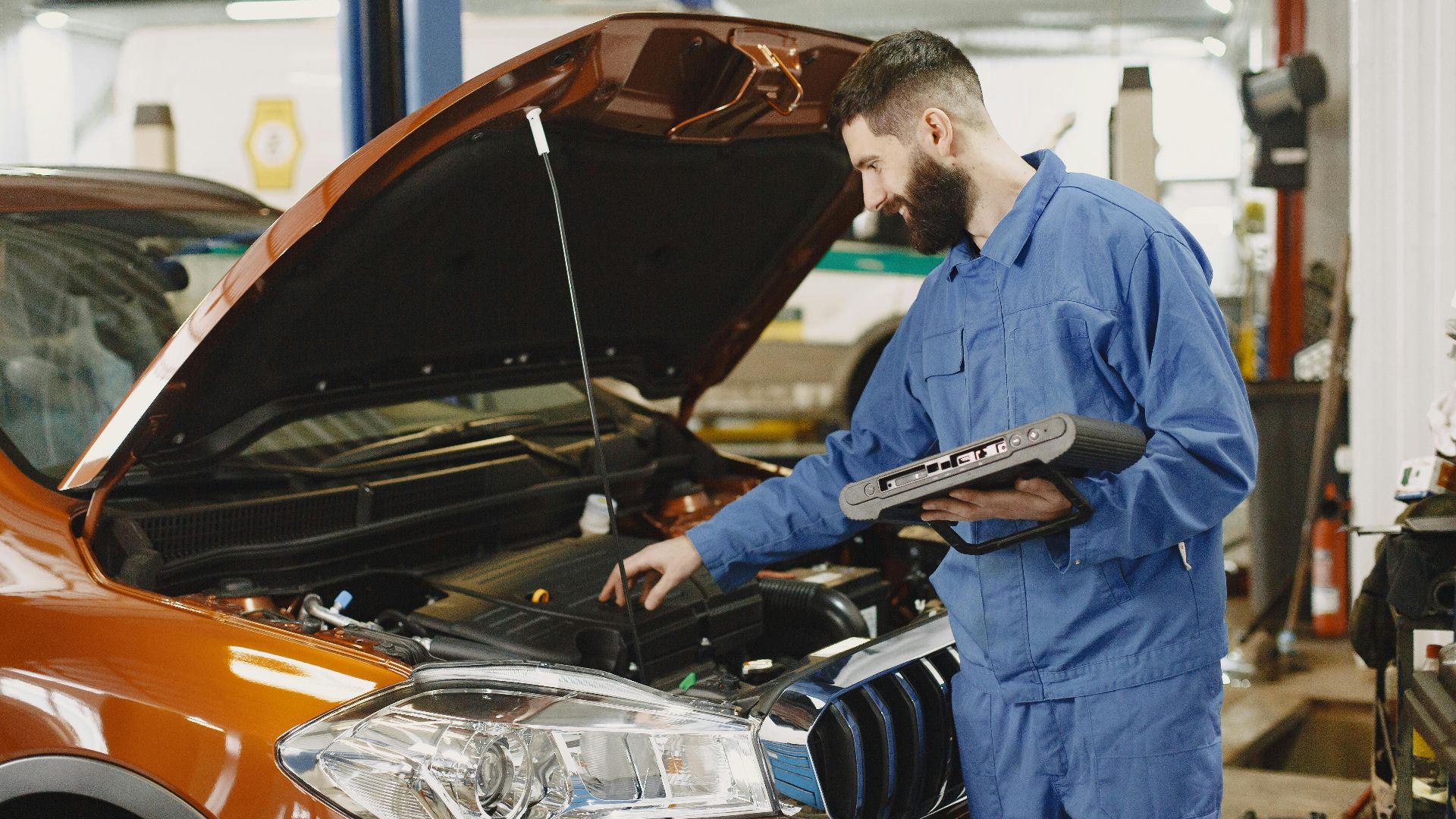 Skilled mechanic working on car engine diagnostics in a modern garage.