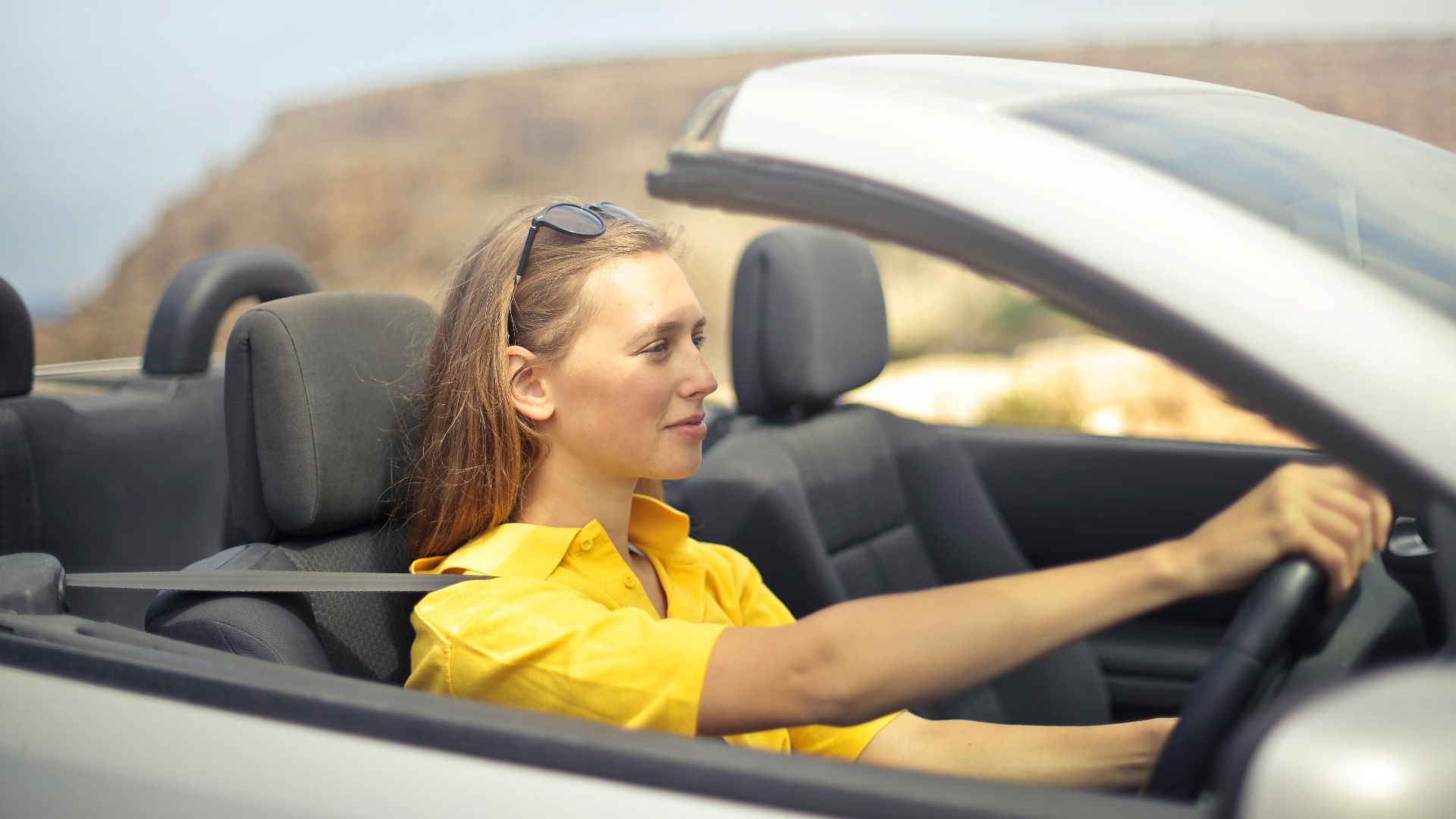 A young woman enjoys driving a convertible on a sunny day in Malta.