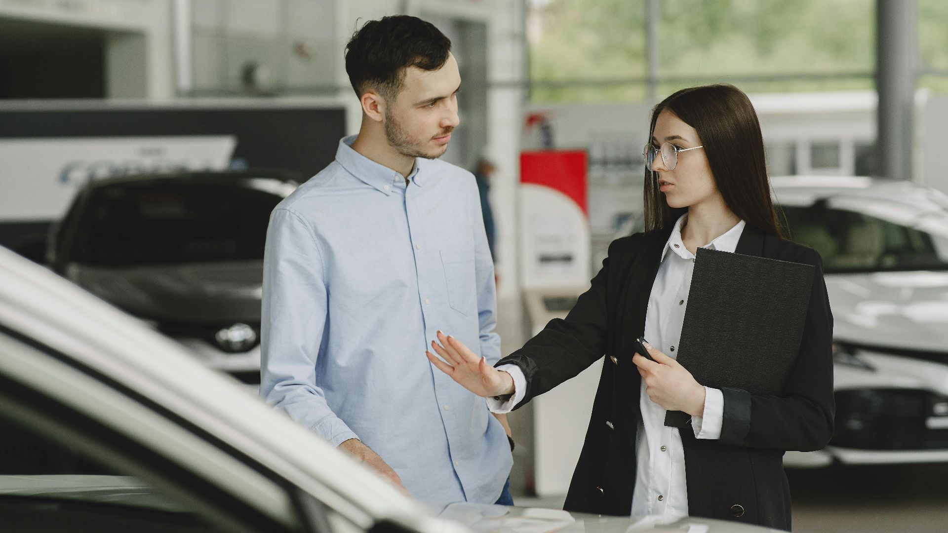 A salesperson and customer discussing car features in a dealership setting.