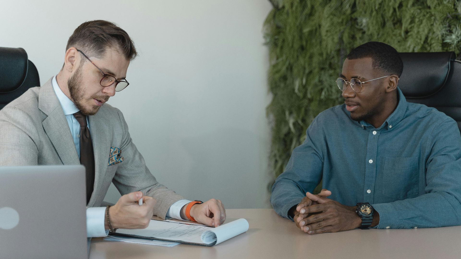 A professional job interview between two men in a modern office environment.