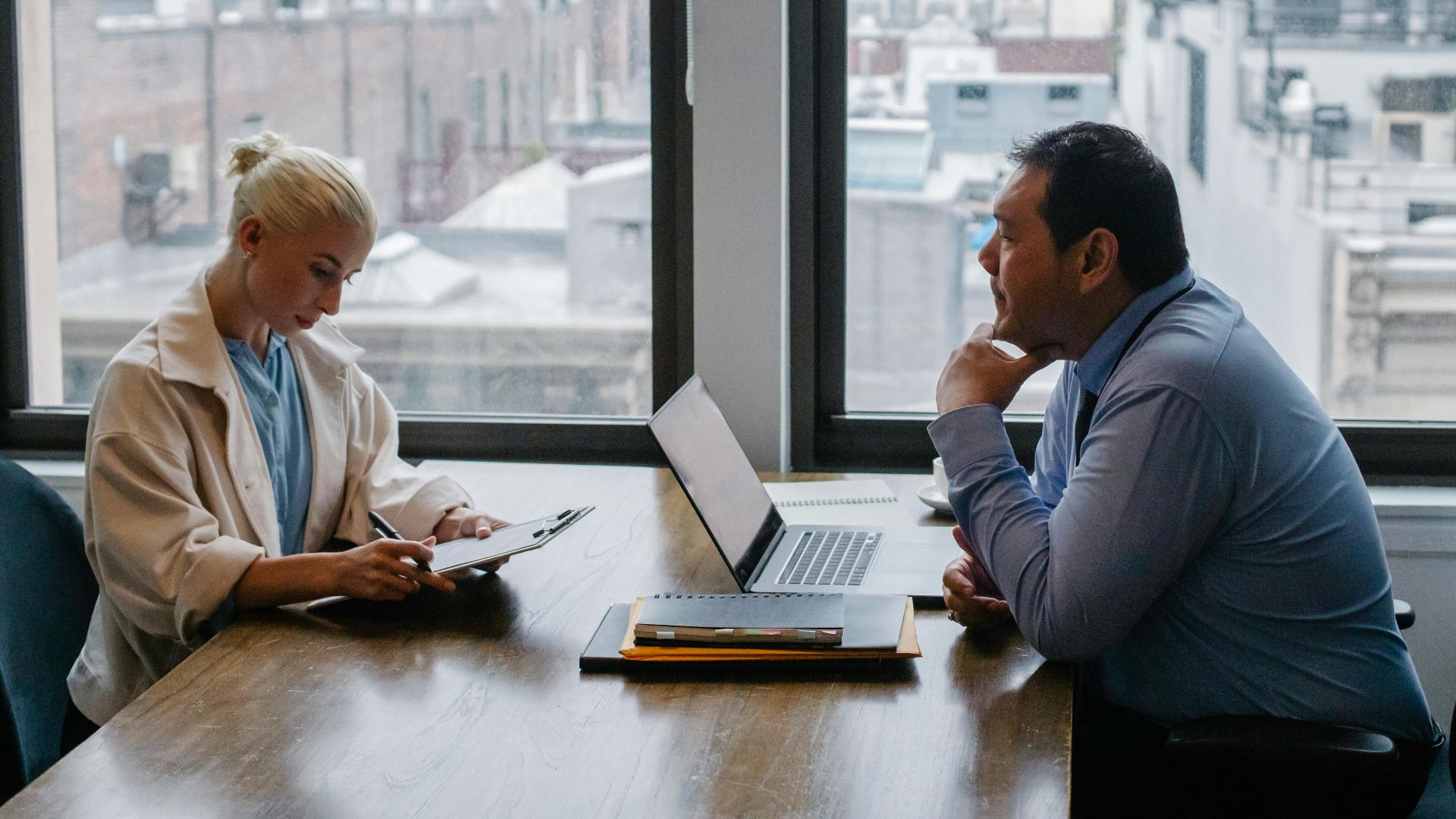 Business meeting between colleagues in a modern office setting with city view.