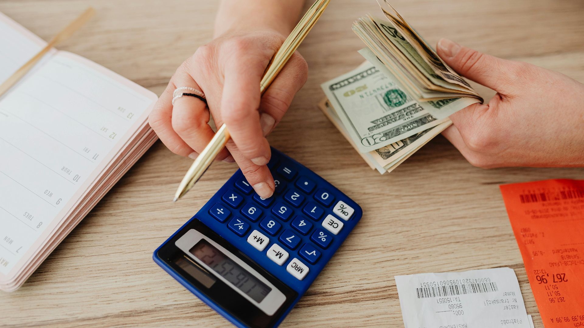 Hands handling cash and calculator for budget planning. Modern financial scene.