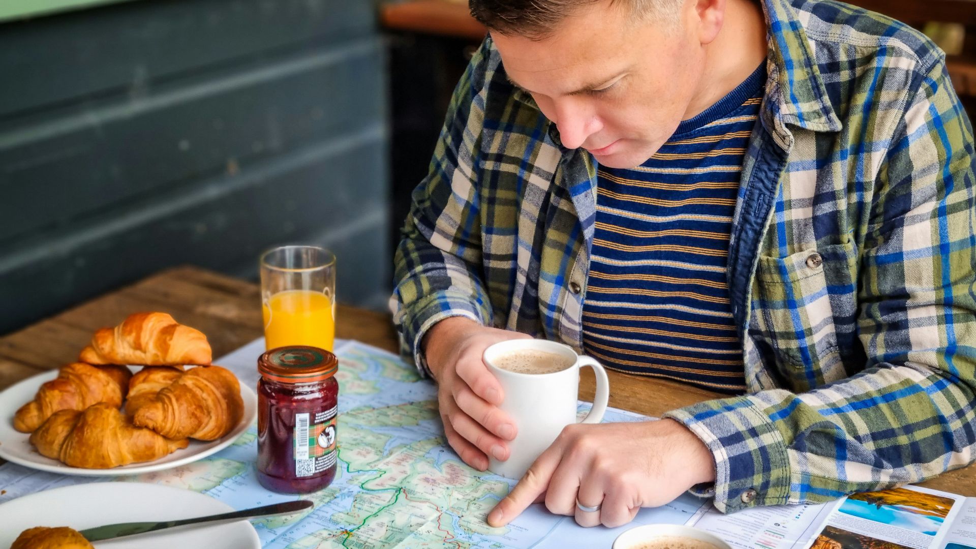 a man sitting at a table with a plate of food and a cup of coffee