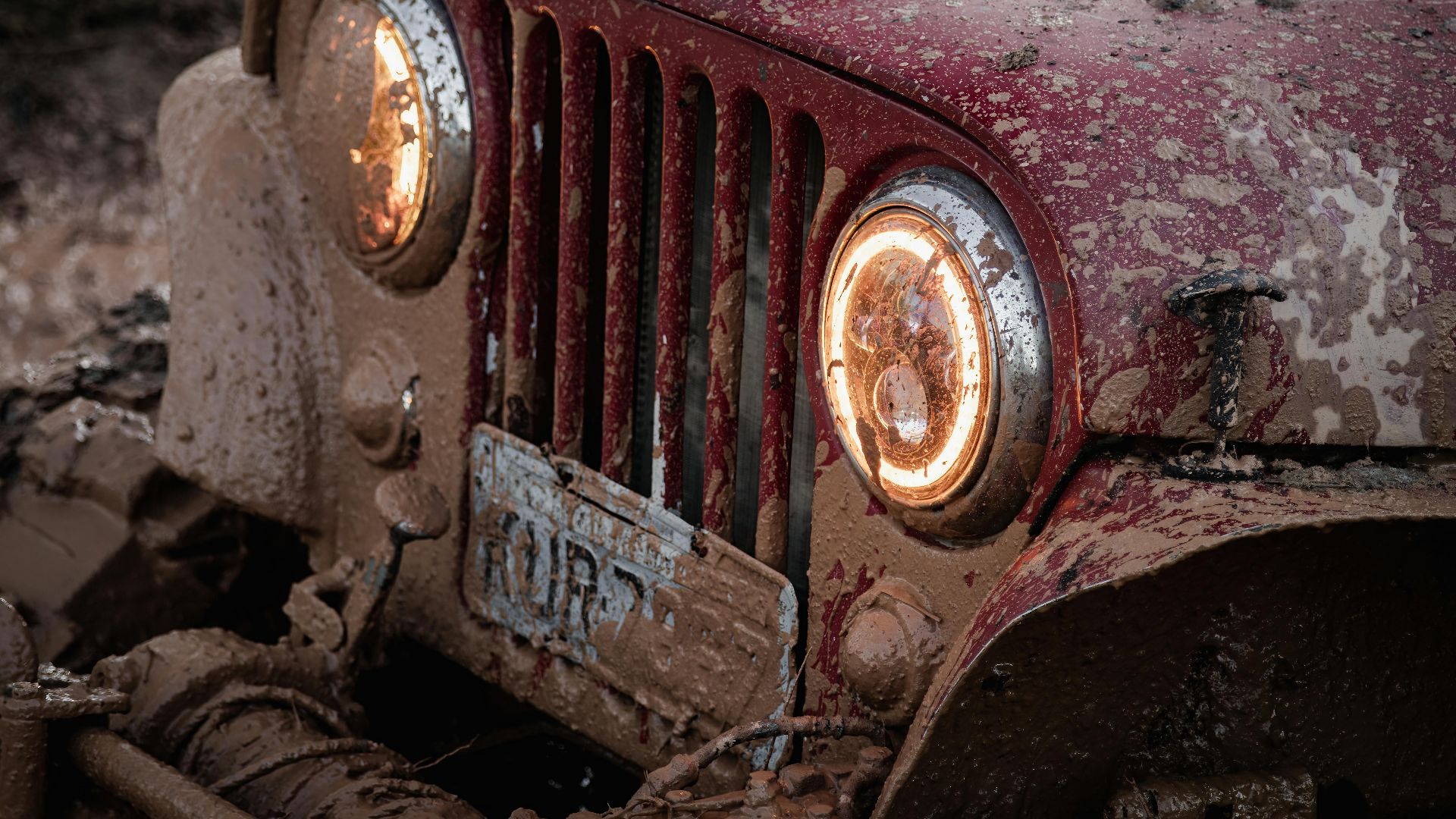 Close-up of a mud-covered vintage 4x4 vehicle highlighting its rugged offroad journey.