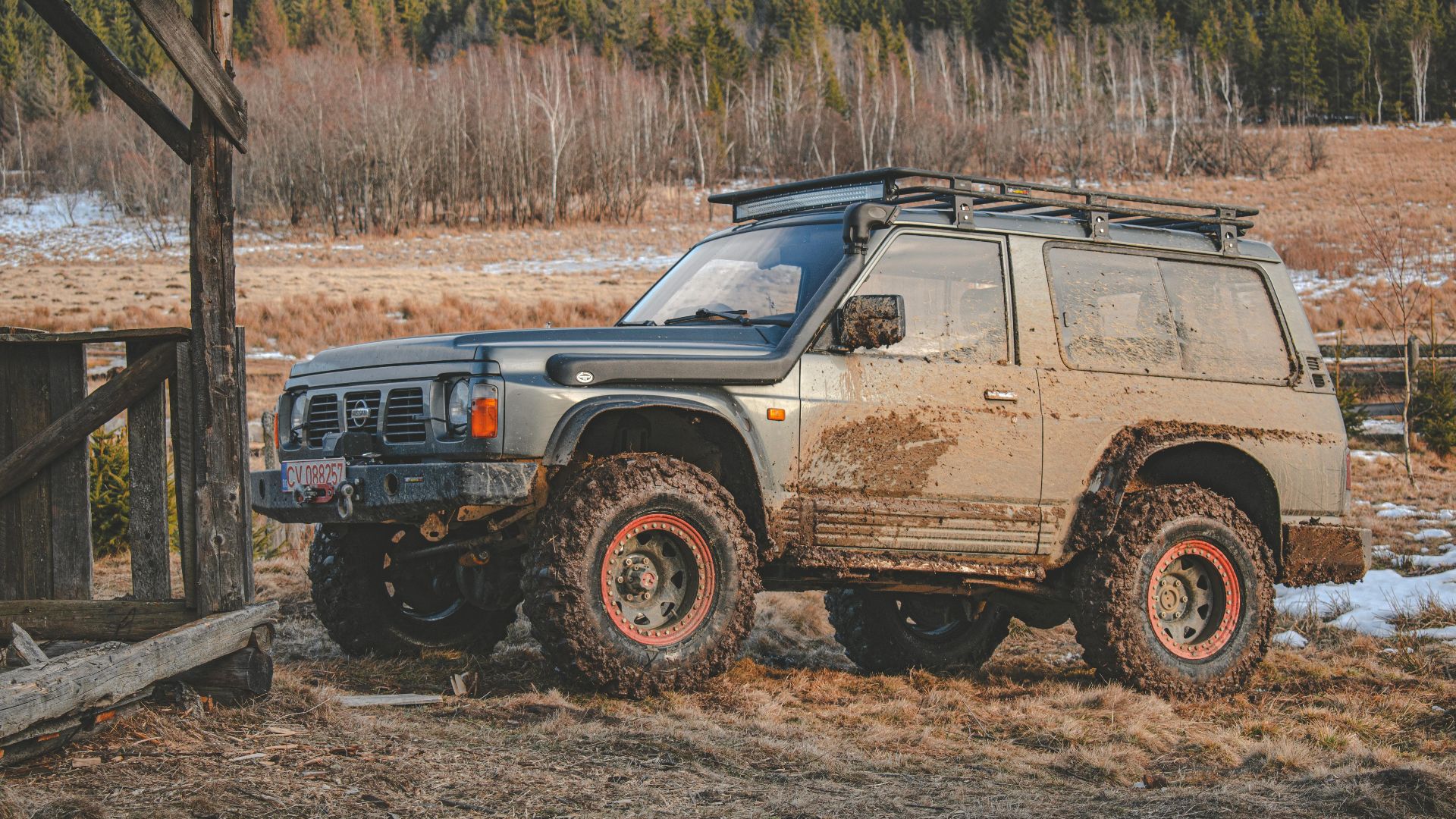 4x4 SUV parked on a muddy trail in Covasna, Romania, amidst a scenic wooded landscape.