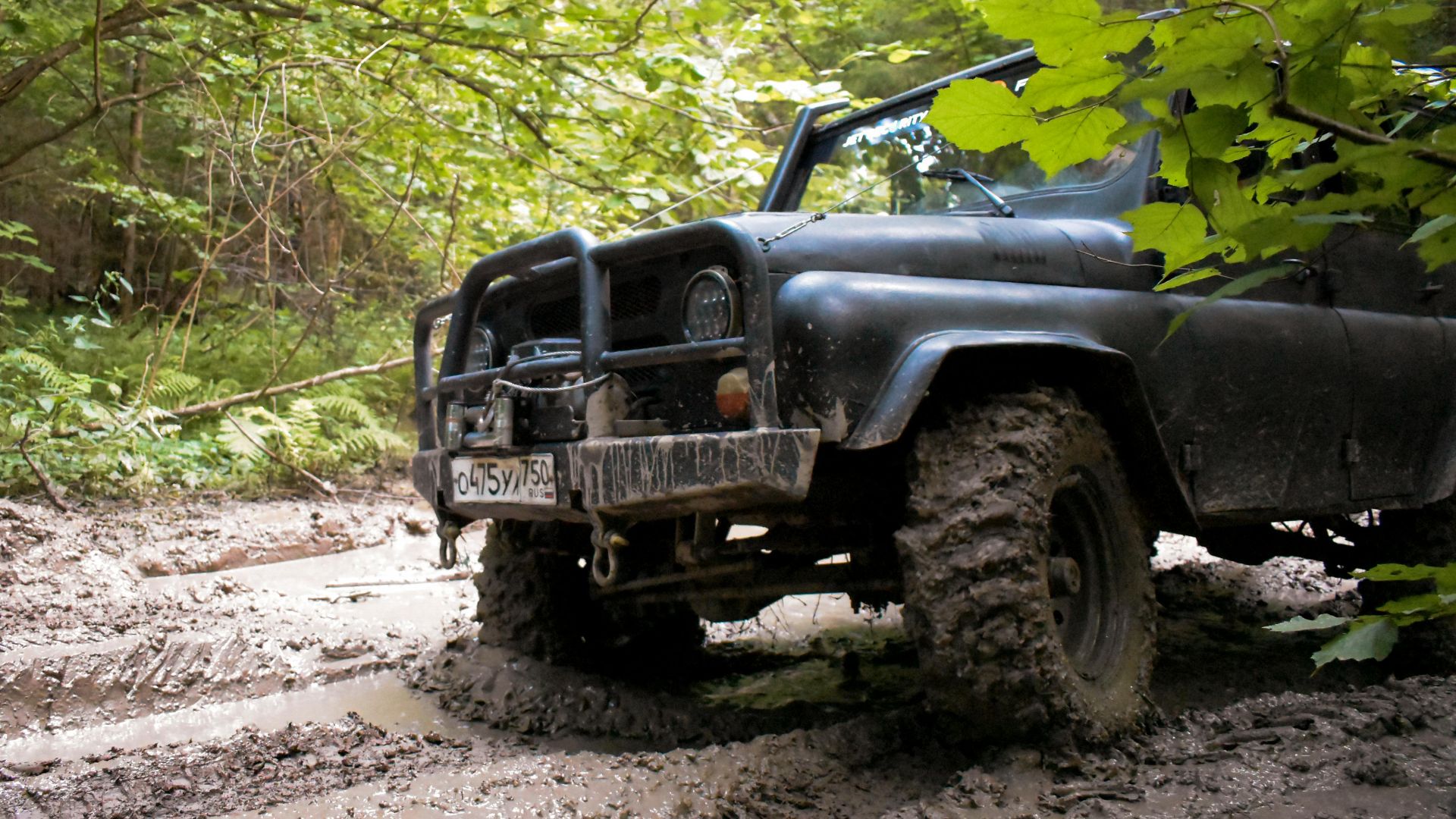 A rugged black SUV on a muddy dirt road in the forest, exemplifying off-road adventure and exploration.