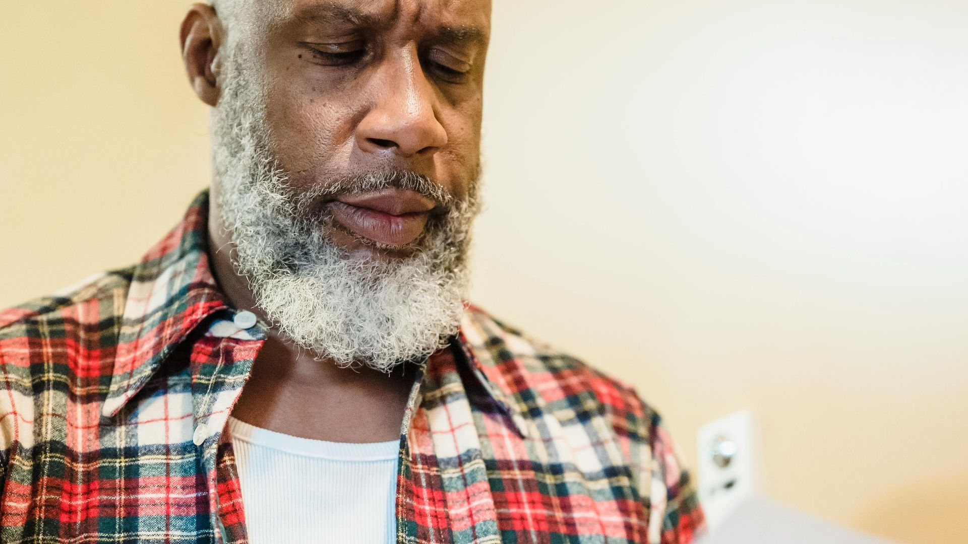 A mature man with a beard attentively reading documents indoors in a focused manner.