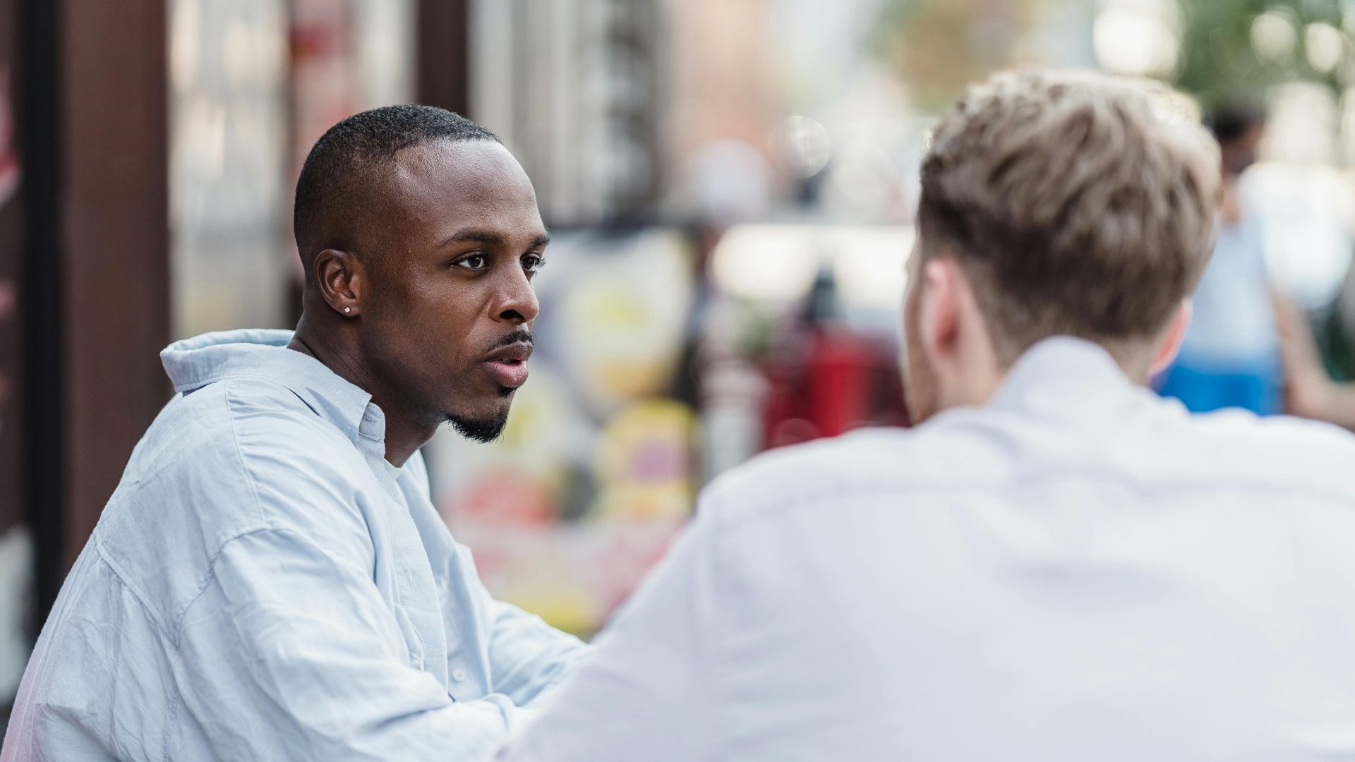 Two men having a conversation in an outdoor setting on a sunny day.
