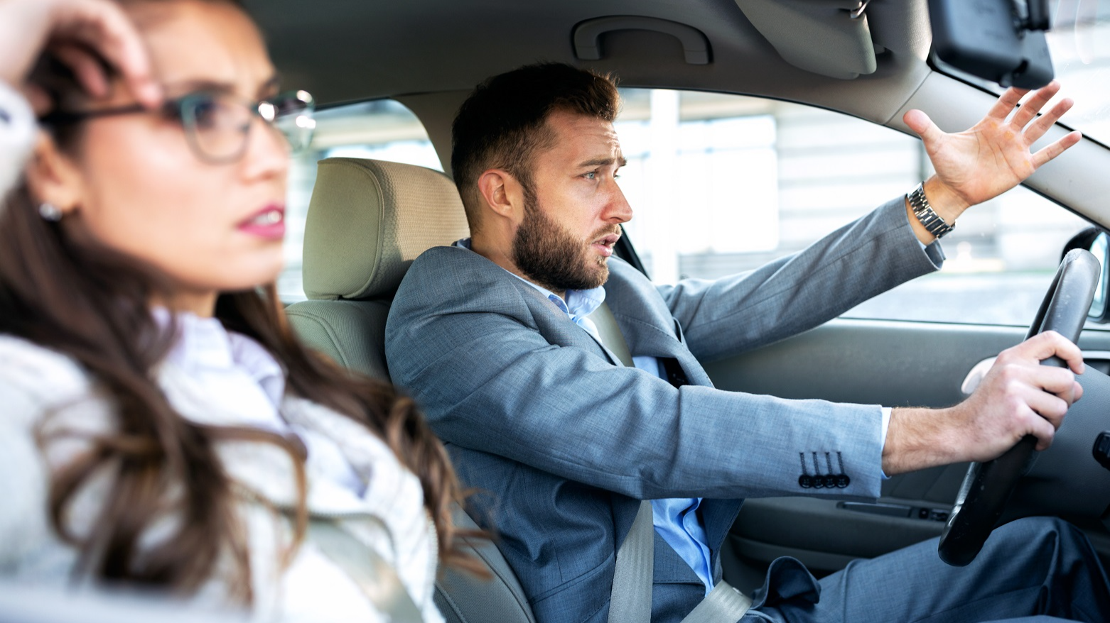 A man and a woman in a stressful situation during car driving with upset faces.