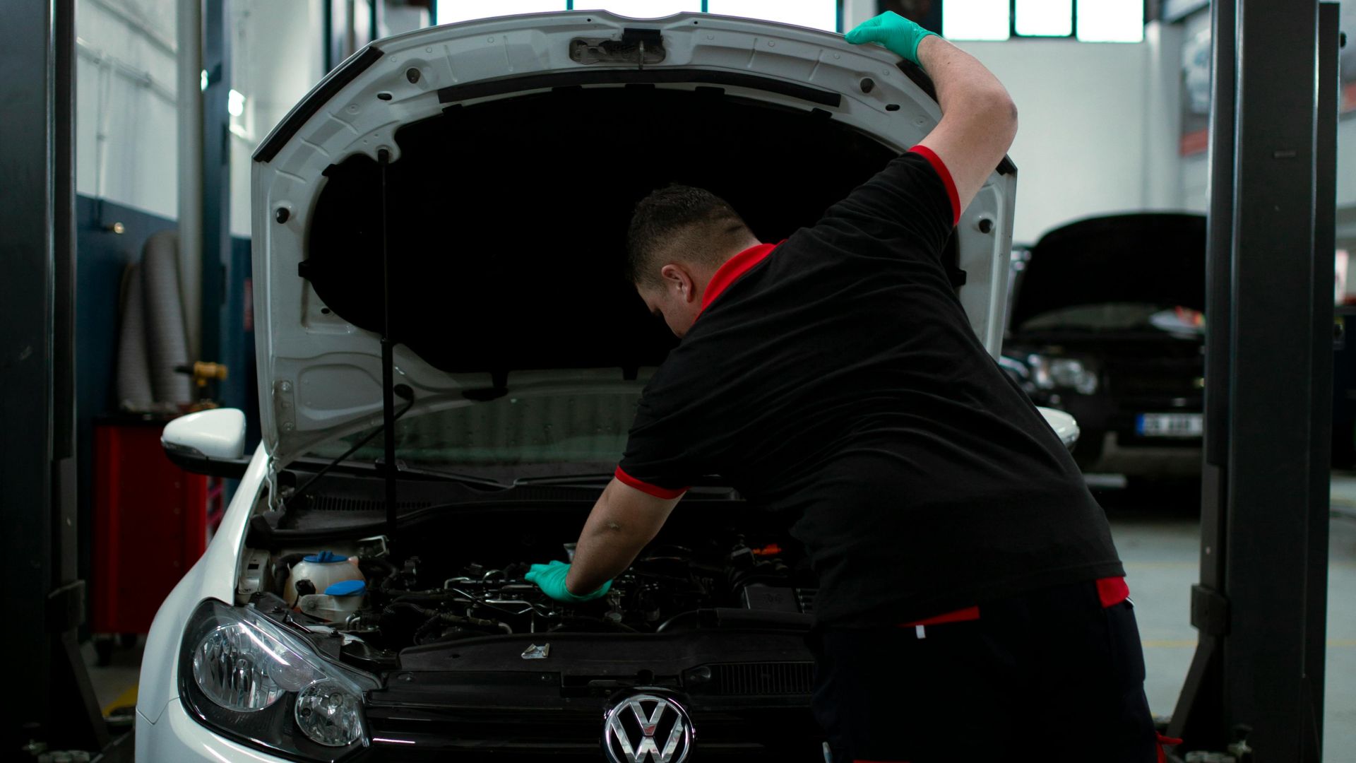 A mechanic works on a Volkswagen engine in an indoor garage setting, showcasing automotive repair skills.