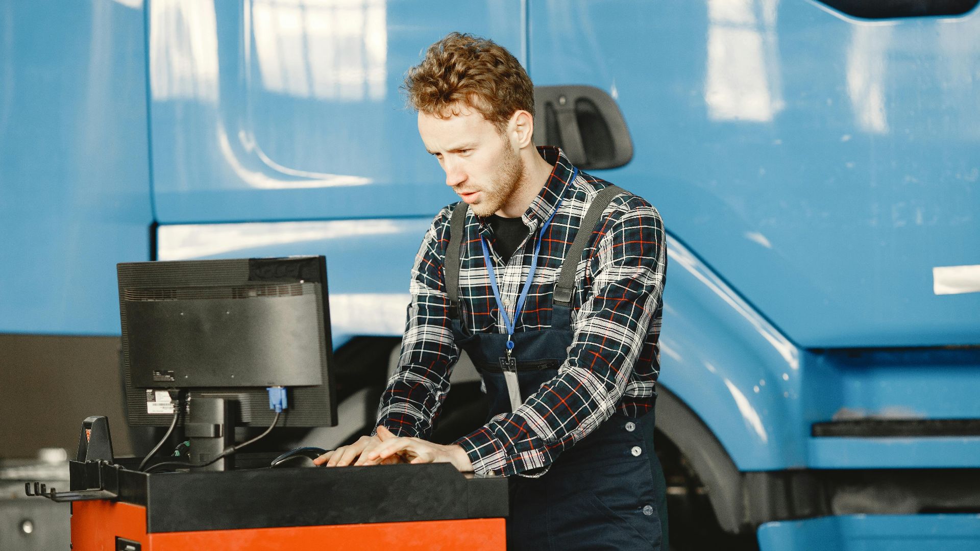 Auto mechanic in a workshop using a computer to diagnose a vehicle.