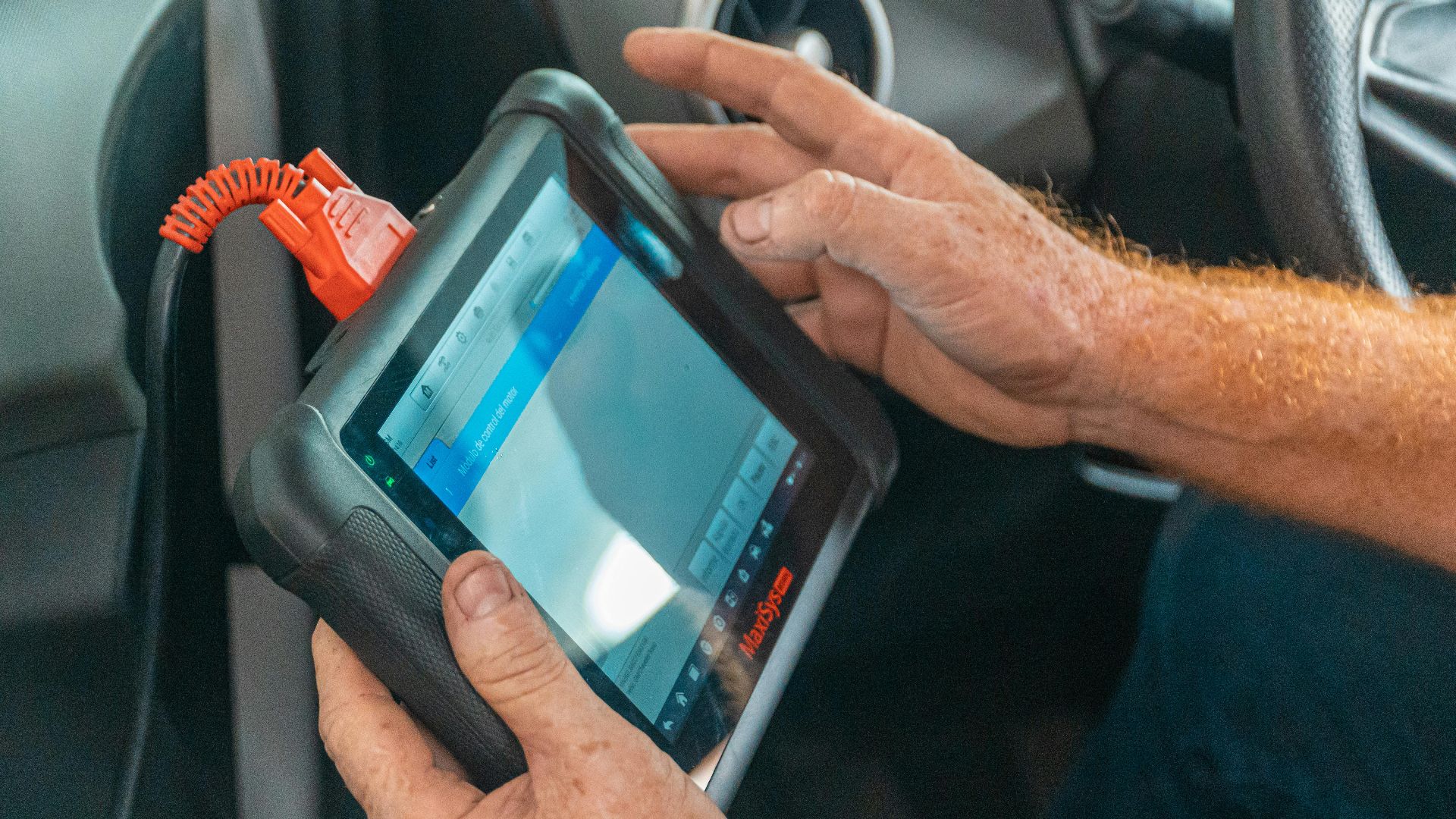 A mechanic uses a diagnostic tablet inside a car for vehicle analysis.
