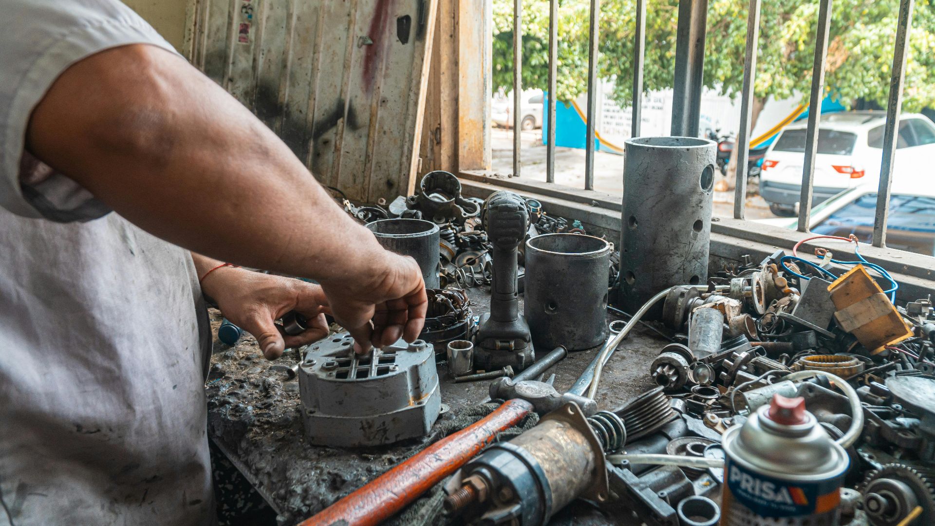 Close-up of a mechanic's hands working with car parts on a workshop table.