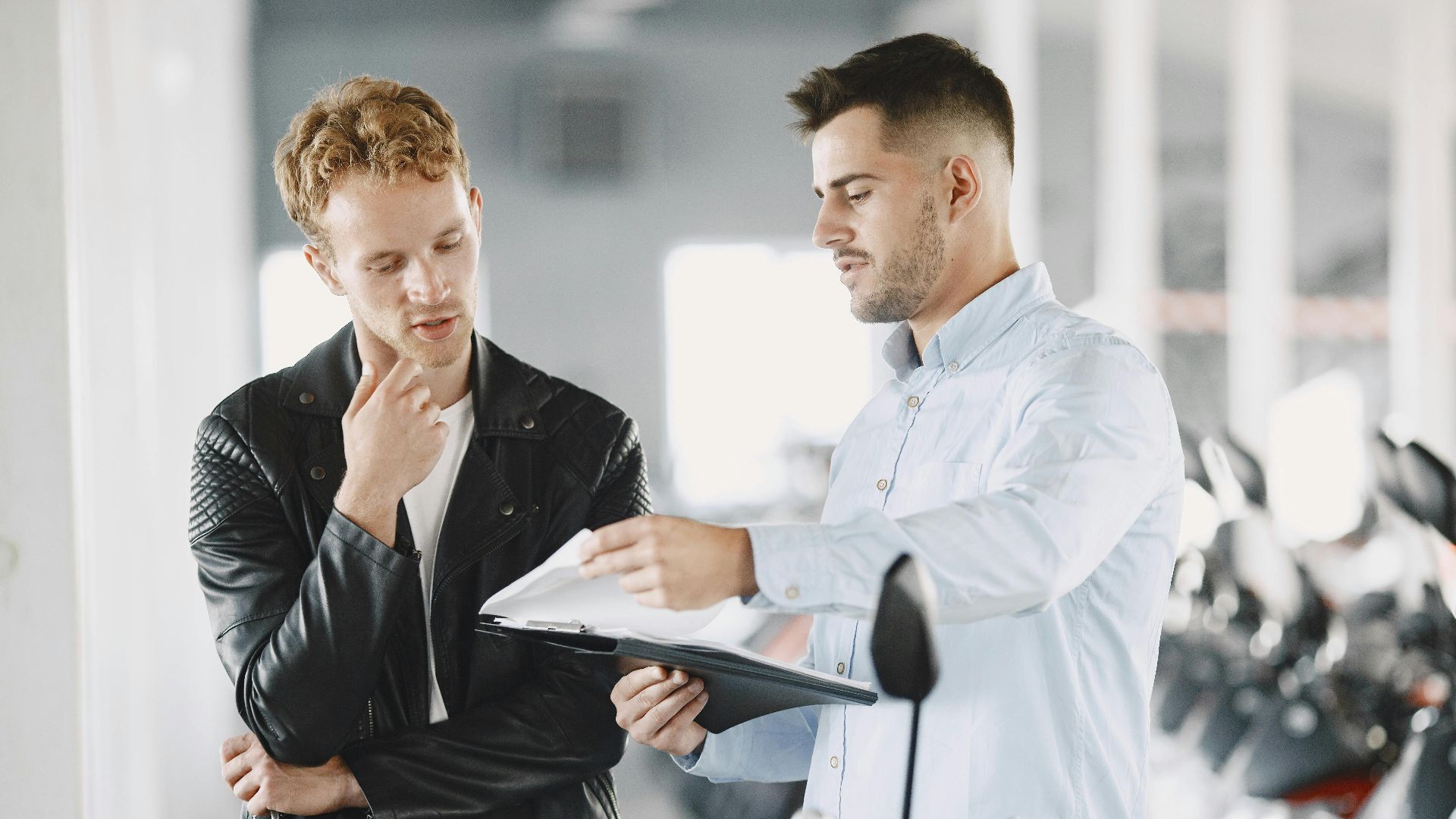Two adults discussing purchasing options at a motorcycle dealership.