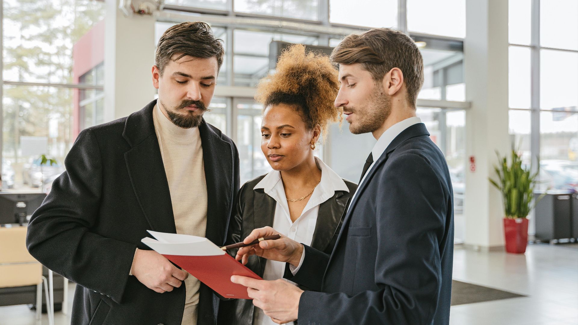 Three professionals discuss documents in a modern office setting, highlighting teamwork and collaboration.