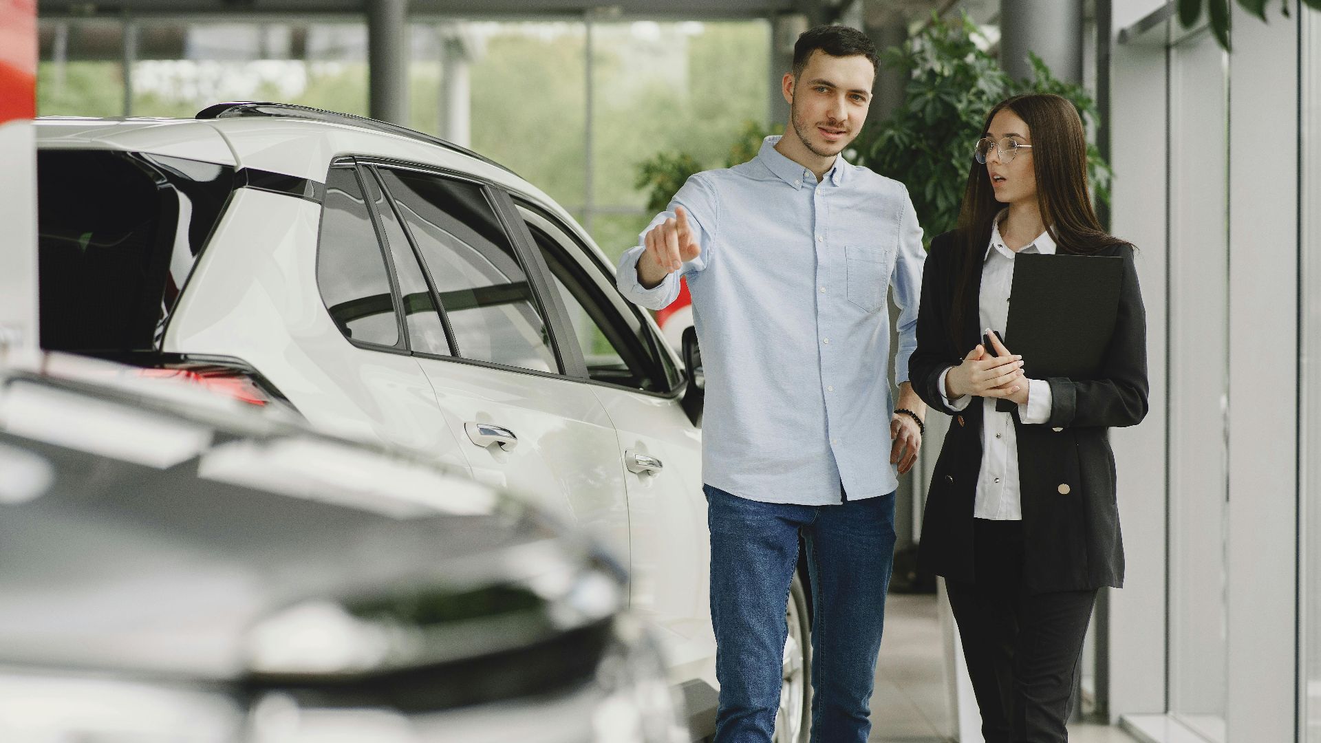 Customer and salesperson discussing a vehicle inside a modern car dealership showroom.