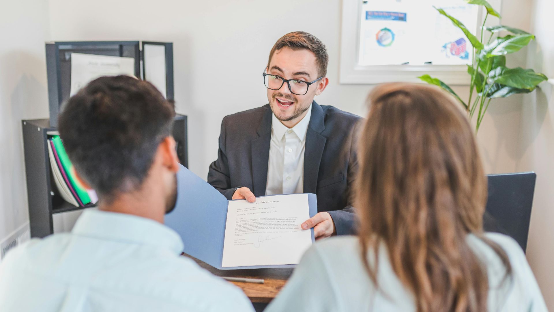 A businessman discusses a contract with clients in a modern office setting.