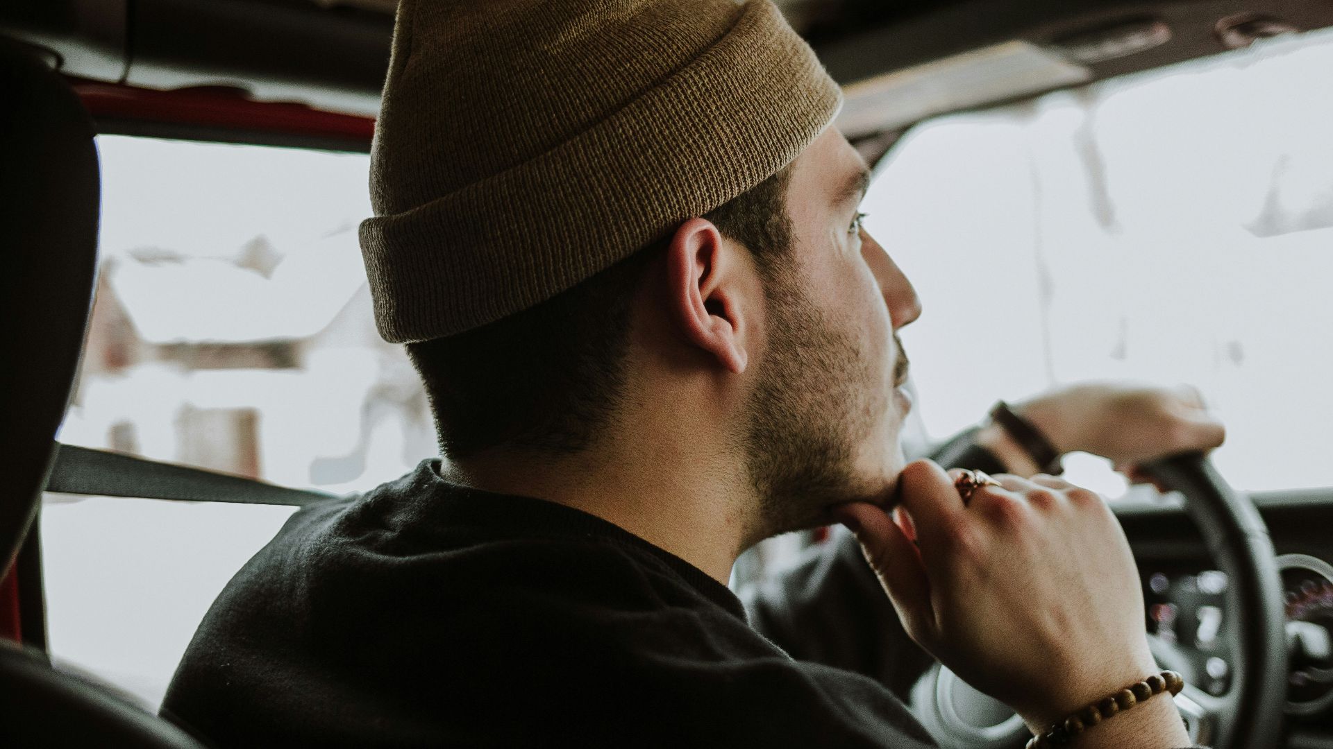 man driving while touching his chin