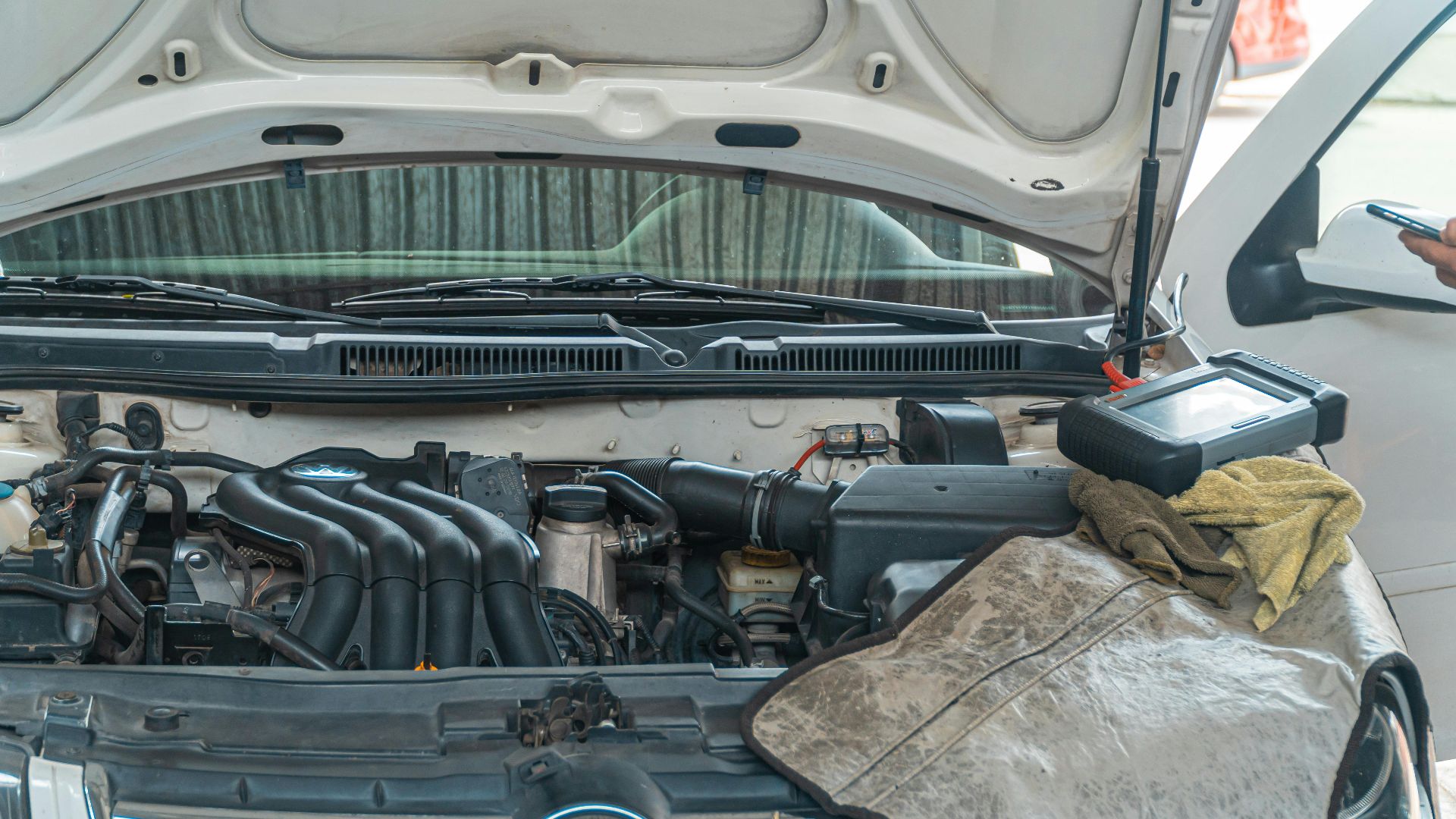 Close-up of a Volkswagen car engine undergoing repair in a garage, tools and diagnostic equipment in use.
