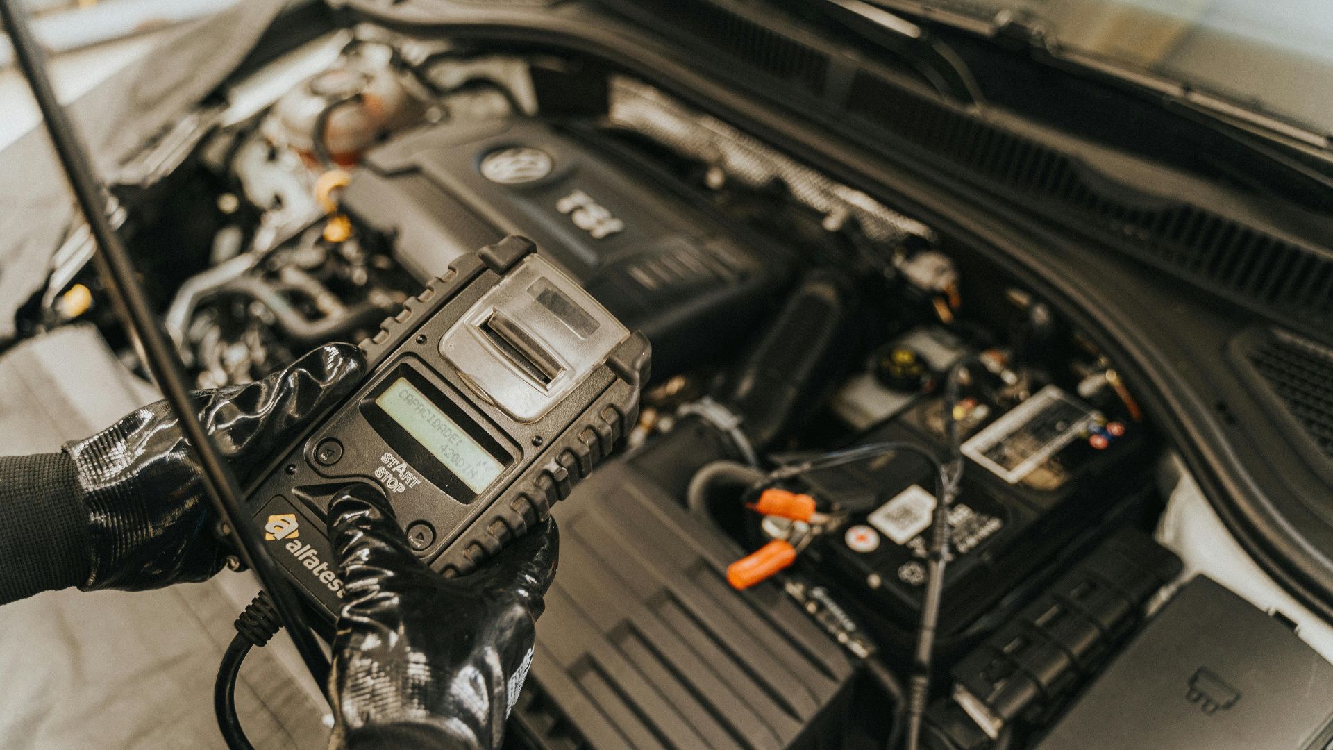 Mechanic diagnosing a car engine with a diagnostic tool, showcasing technical expertise and automotive care.