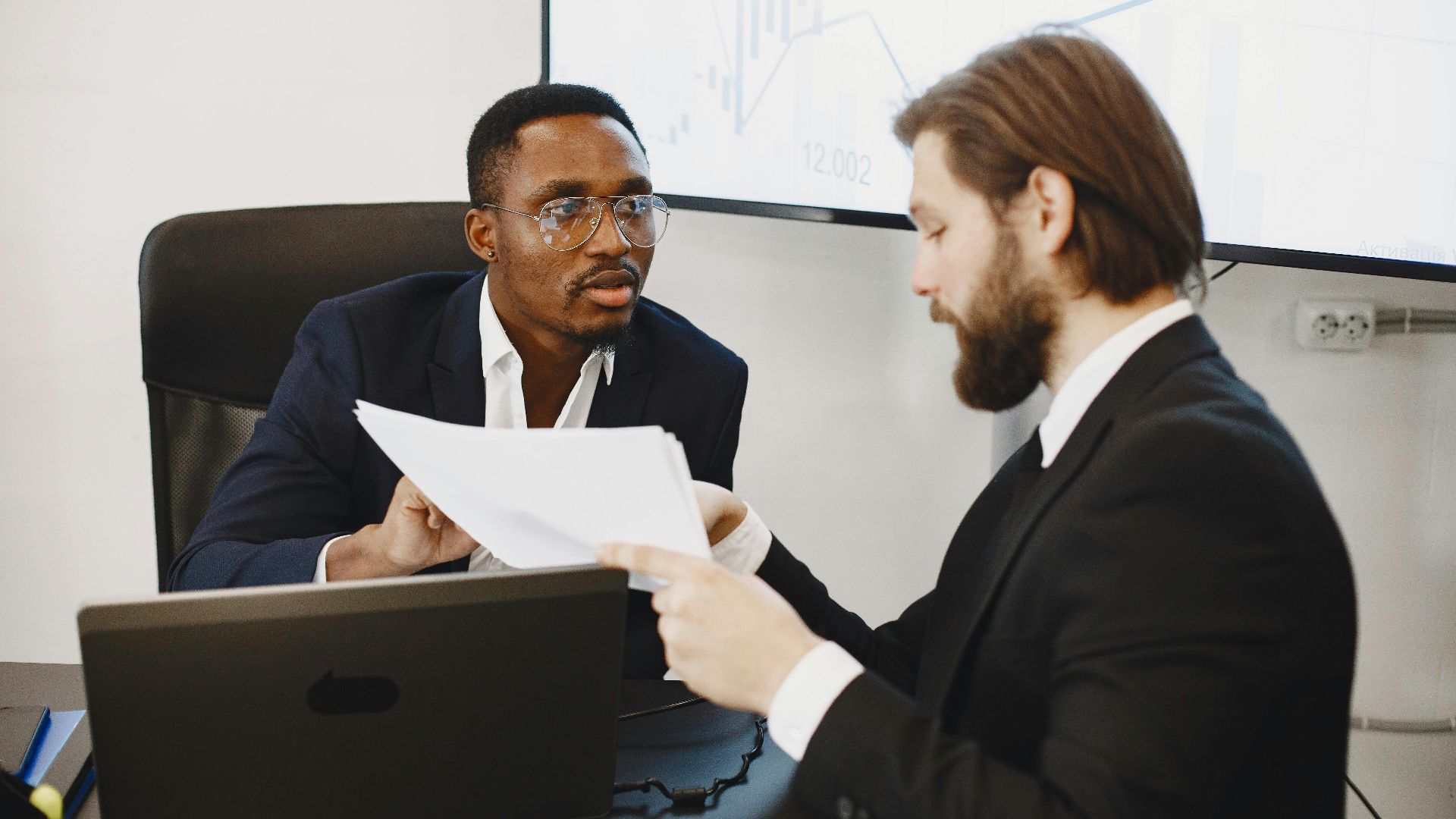 Professionals examining documents in an office business meeting setup.