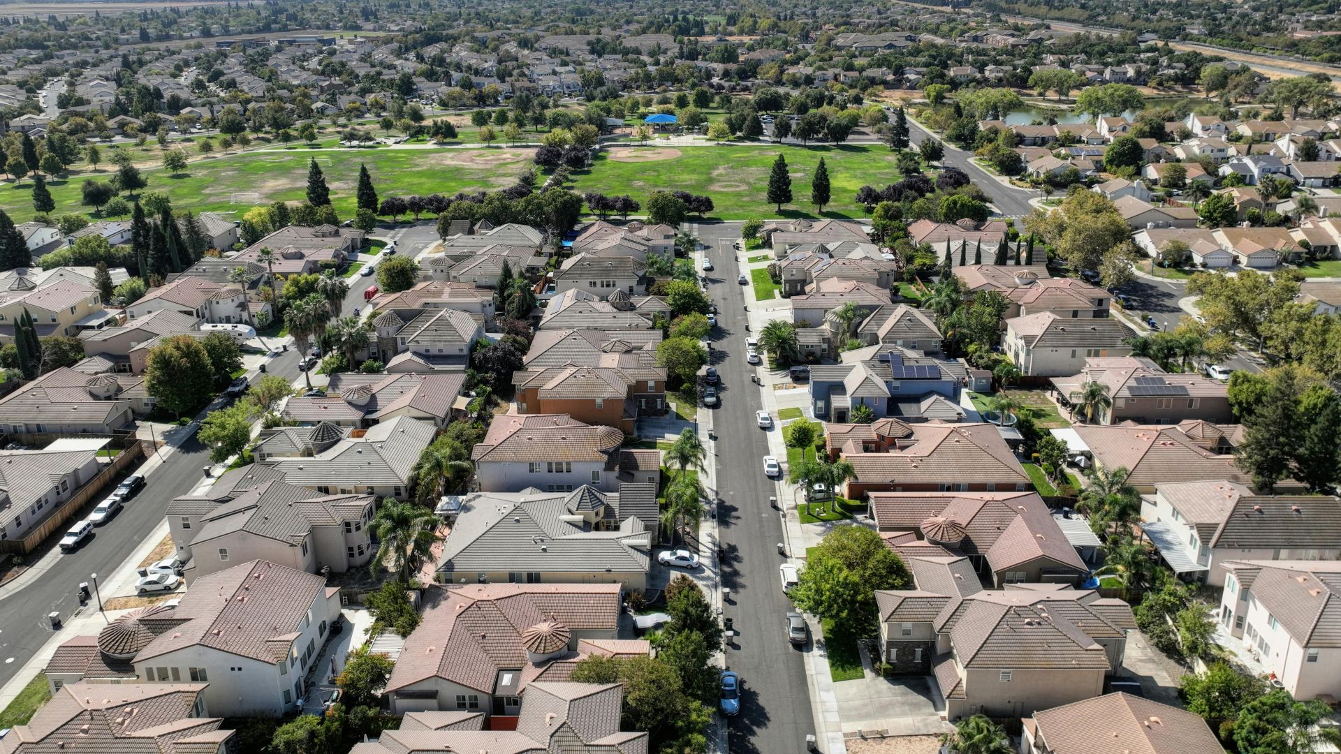 Scenic aerial view of Sacramento suburb with rows of houses and lush greenery on a sunny day.
