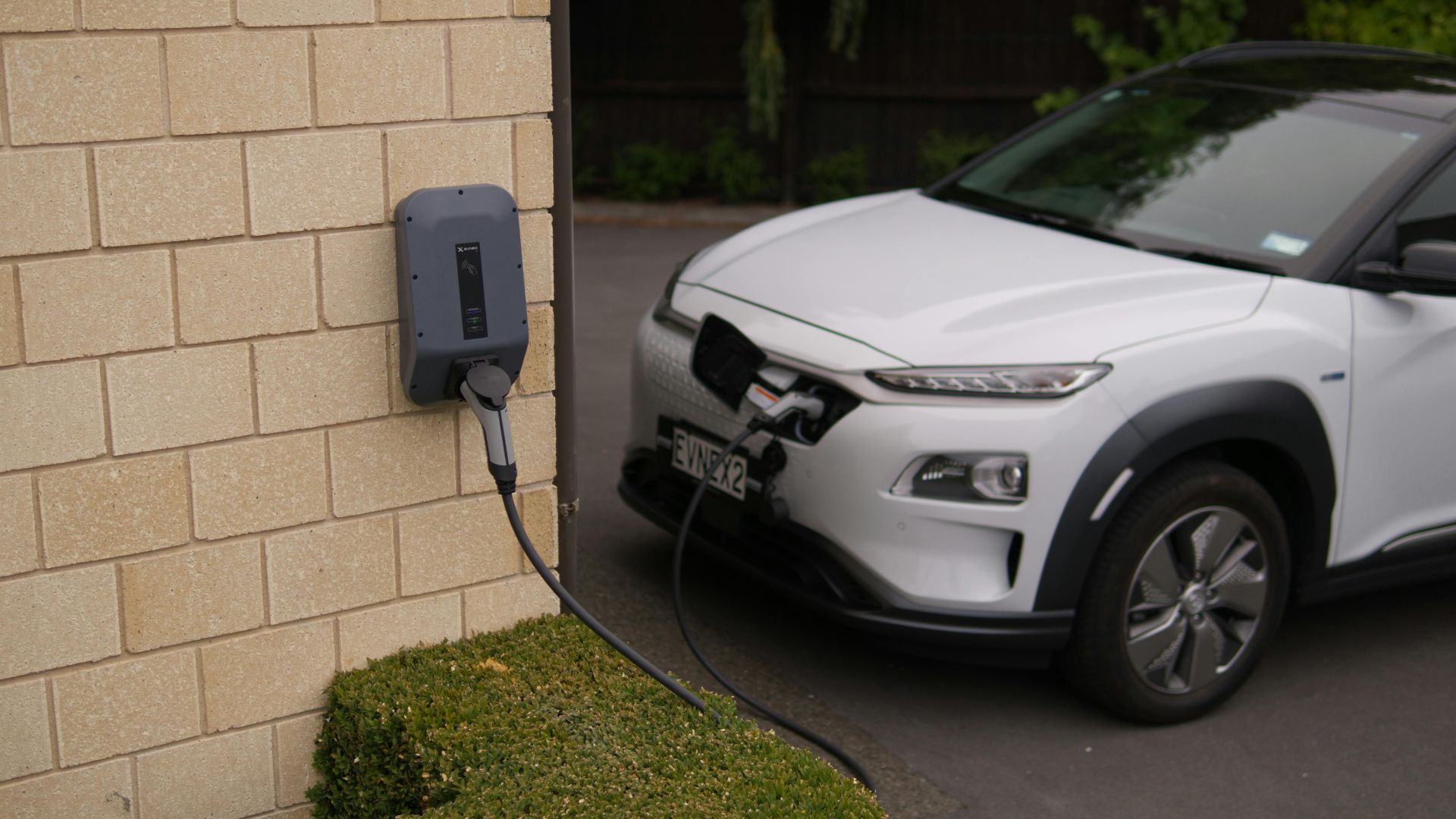 A white electric car charging at a station in Christchurch, New Zealand, showcasing modern eco-friendly transportation.