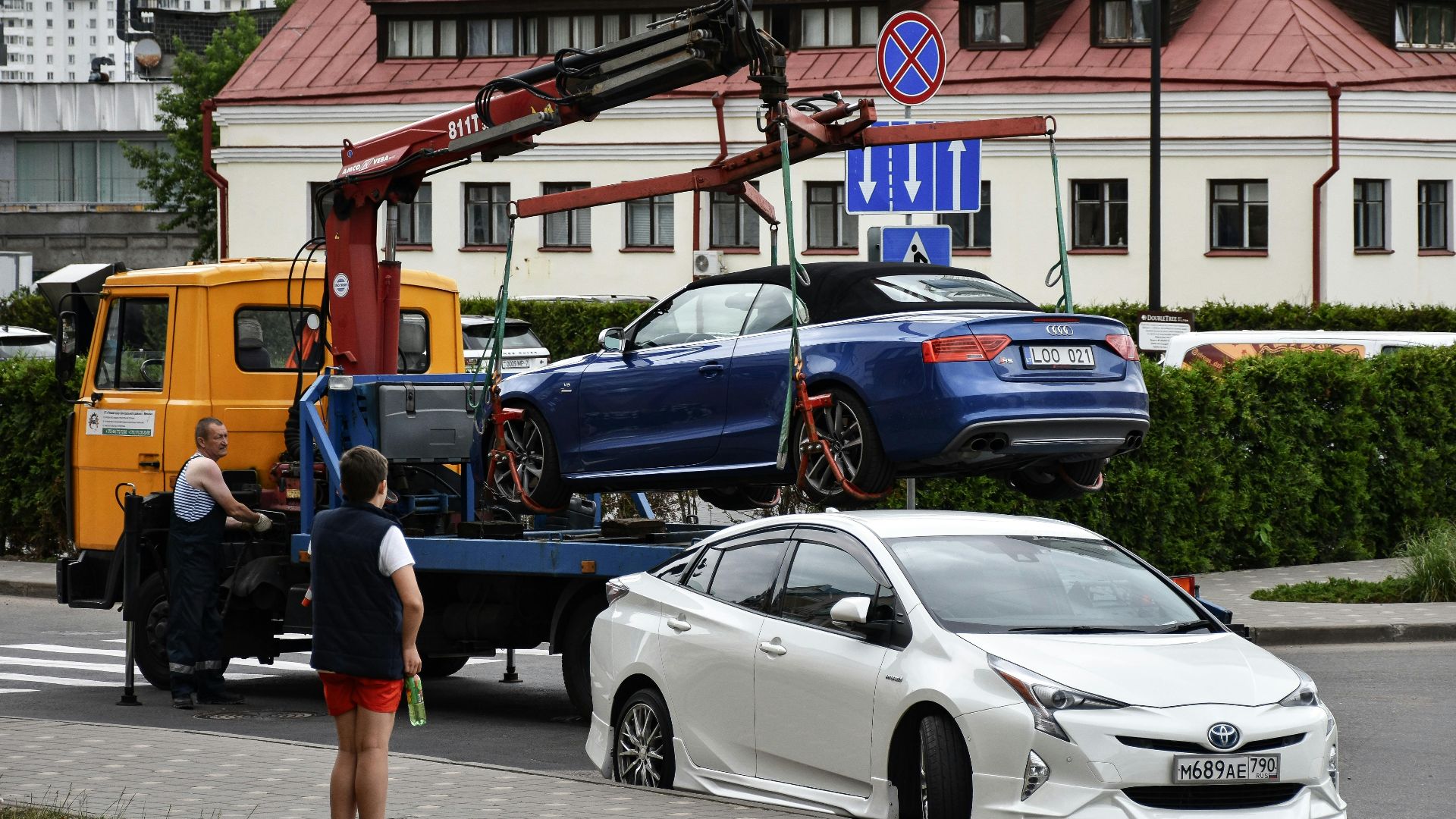 Towing a blue Audi convertible in a bustling city street.