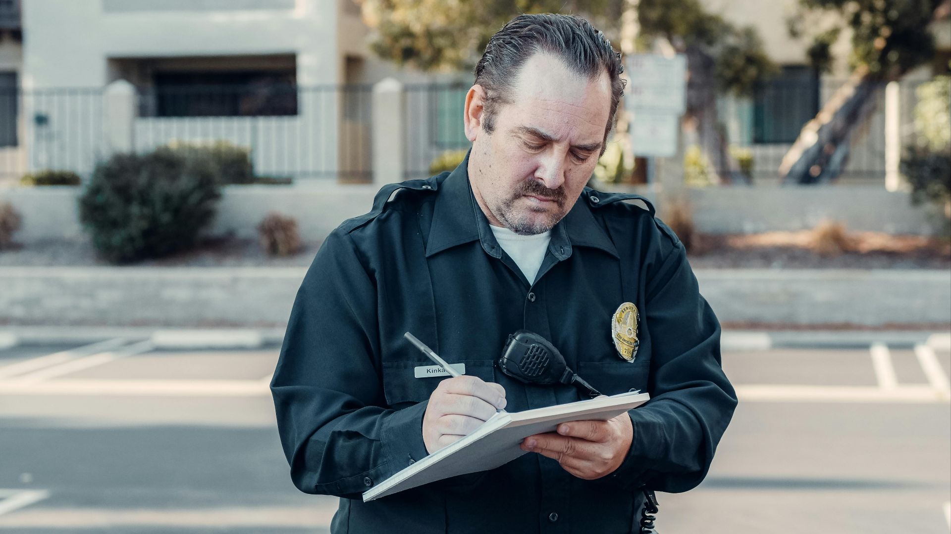 Police officer in uniform writing a ticket on a clipboard outdoors.