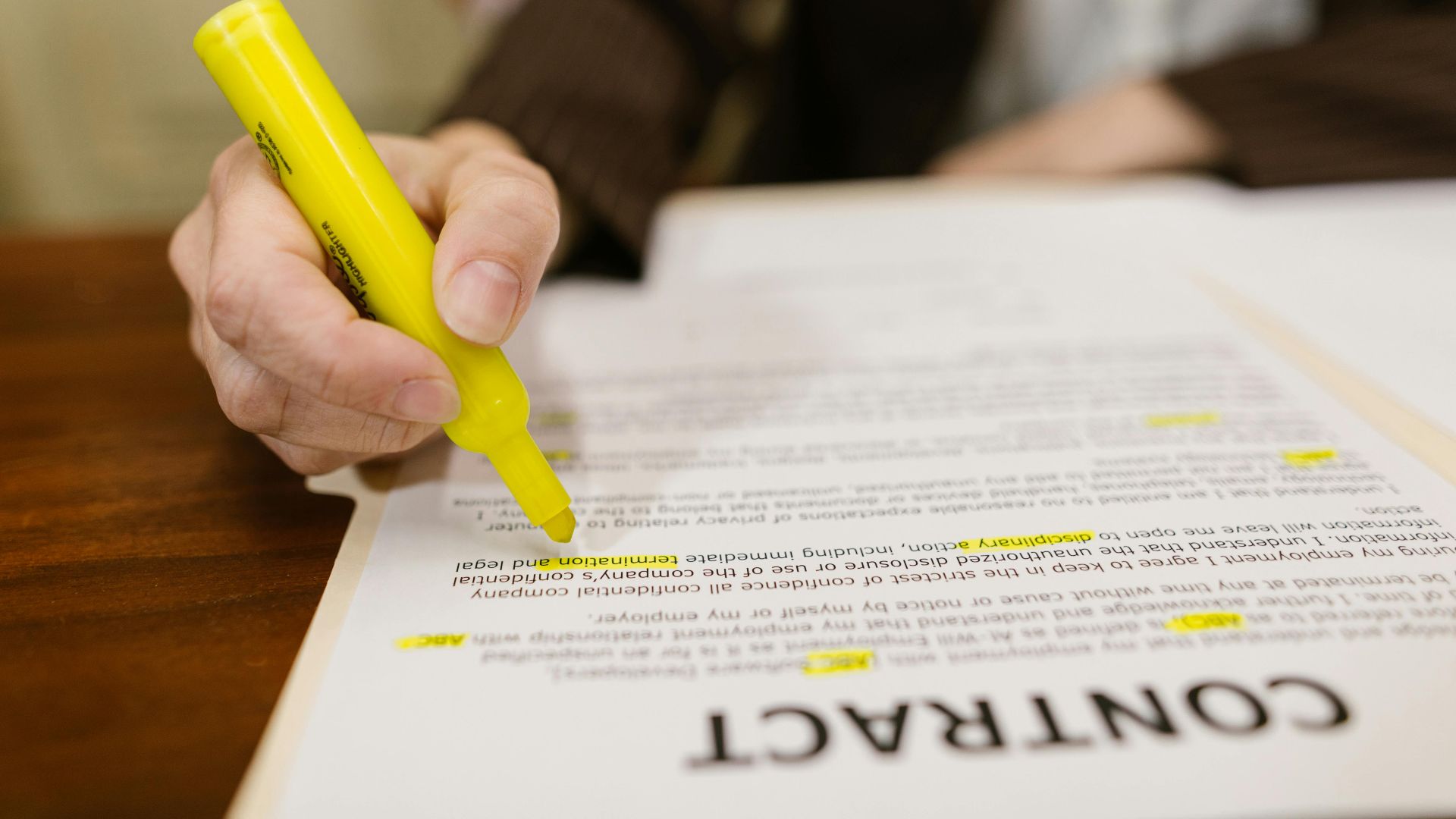A close-up of a hand highlighting a contract, emphasizing important legal terms.