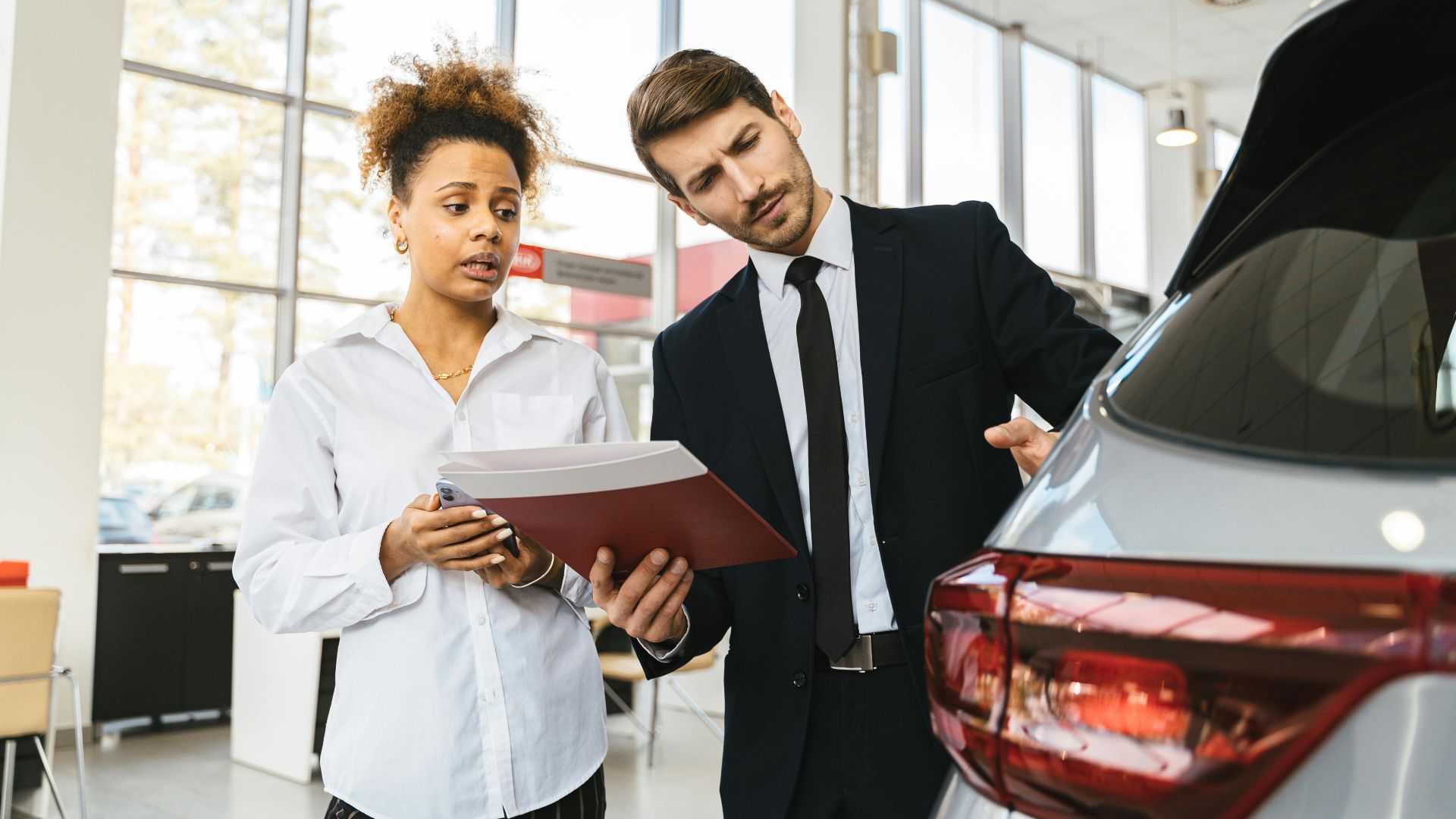 A professional consultation at a car dealership involving a sales agent and a customer discussing a vehicle purchase.