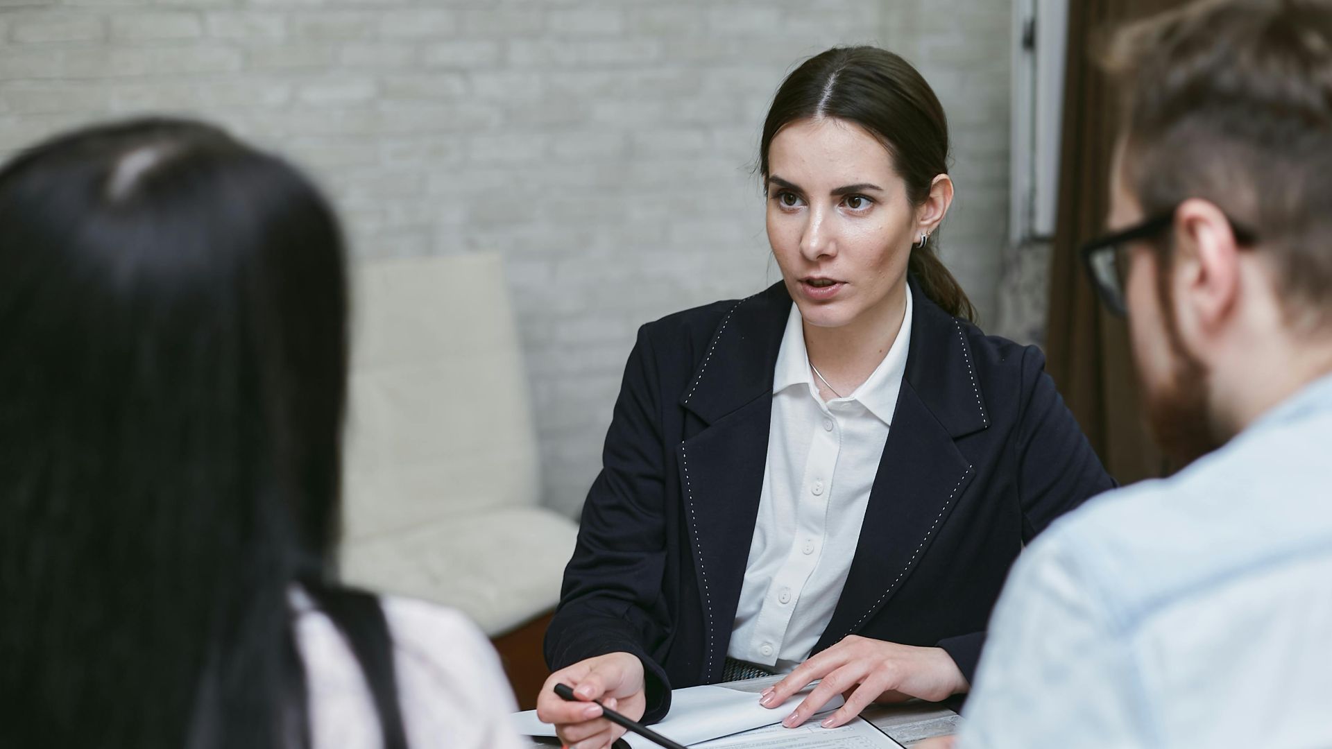 Three colleagues engaged in a business meeting discussing documents at a table indoors.