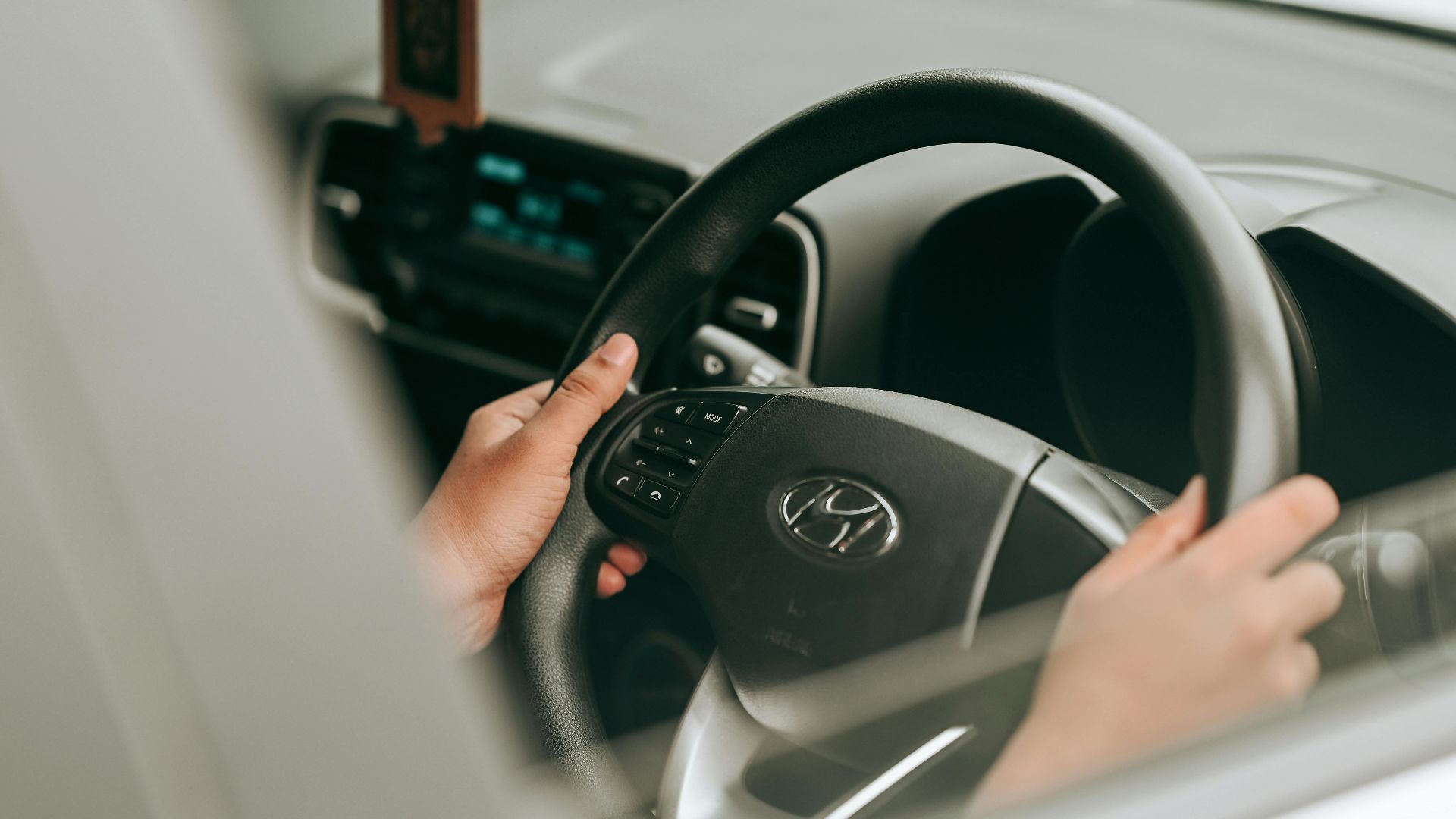 Close-up view of hands holding the steering wheel inside a car.