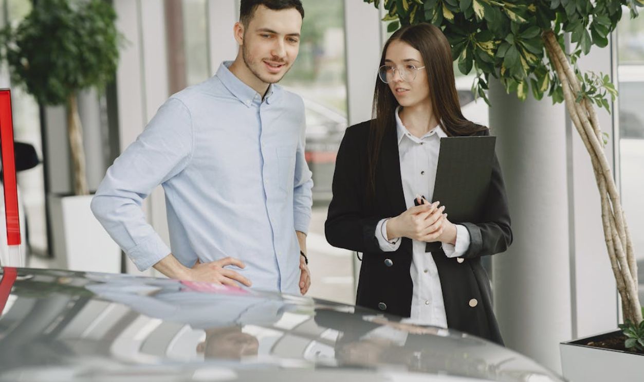 Two professionals discussing business in a modern car showroom with plants around